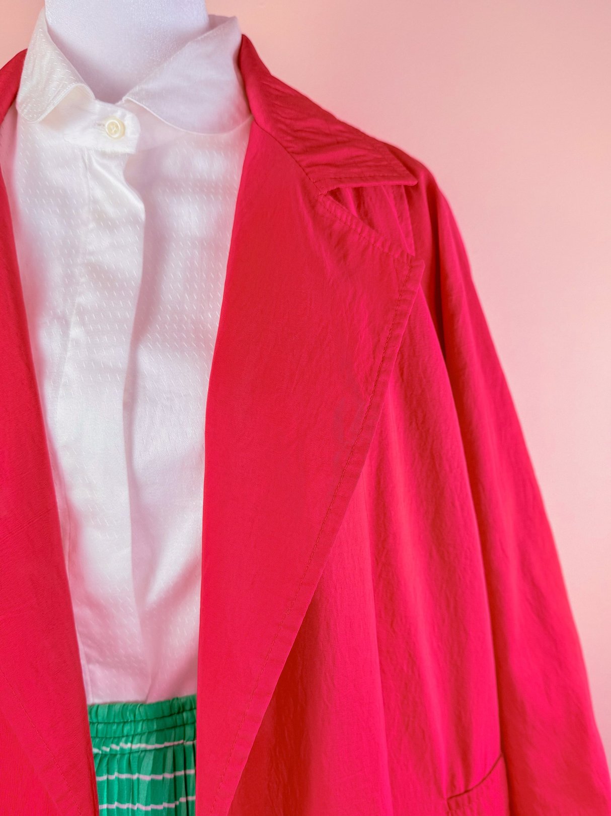 Red 1980s women's Poppy Forecast Rain Jacket displayed on a mannequin, paired with a white button-up shirt and green-striped skirt.