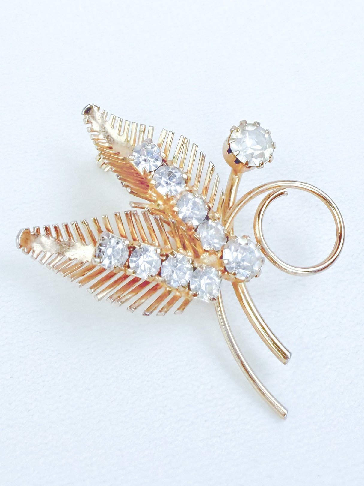 Gold-tone 1950s Gilded Fern Brooch featuring sparkling clear rhinestones arranged in a leaf design.