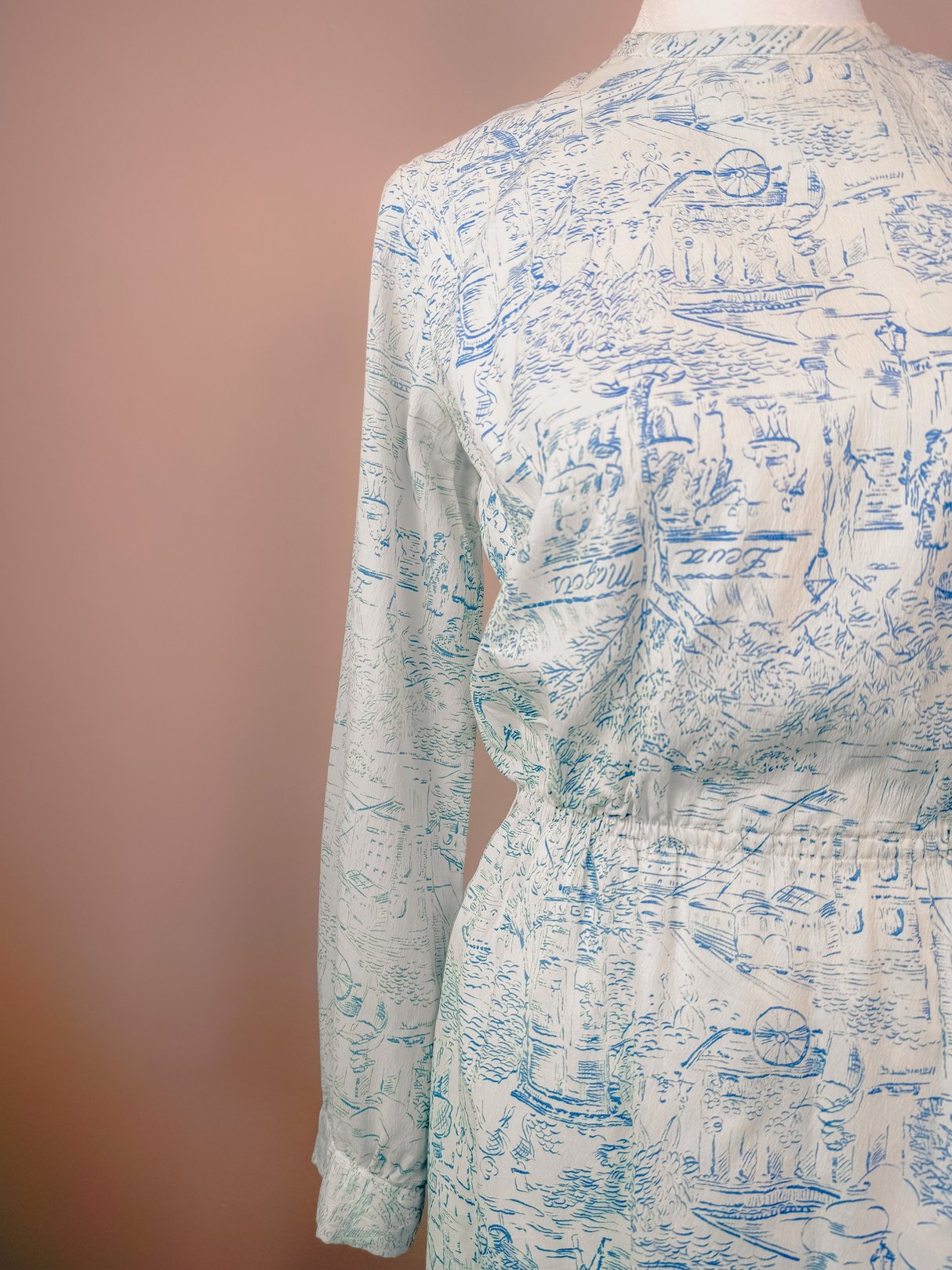 A blue 1960s women's dress featuring a montage print with long sleeves and an elastic waistband.
