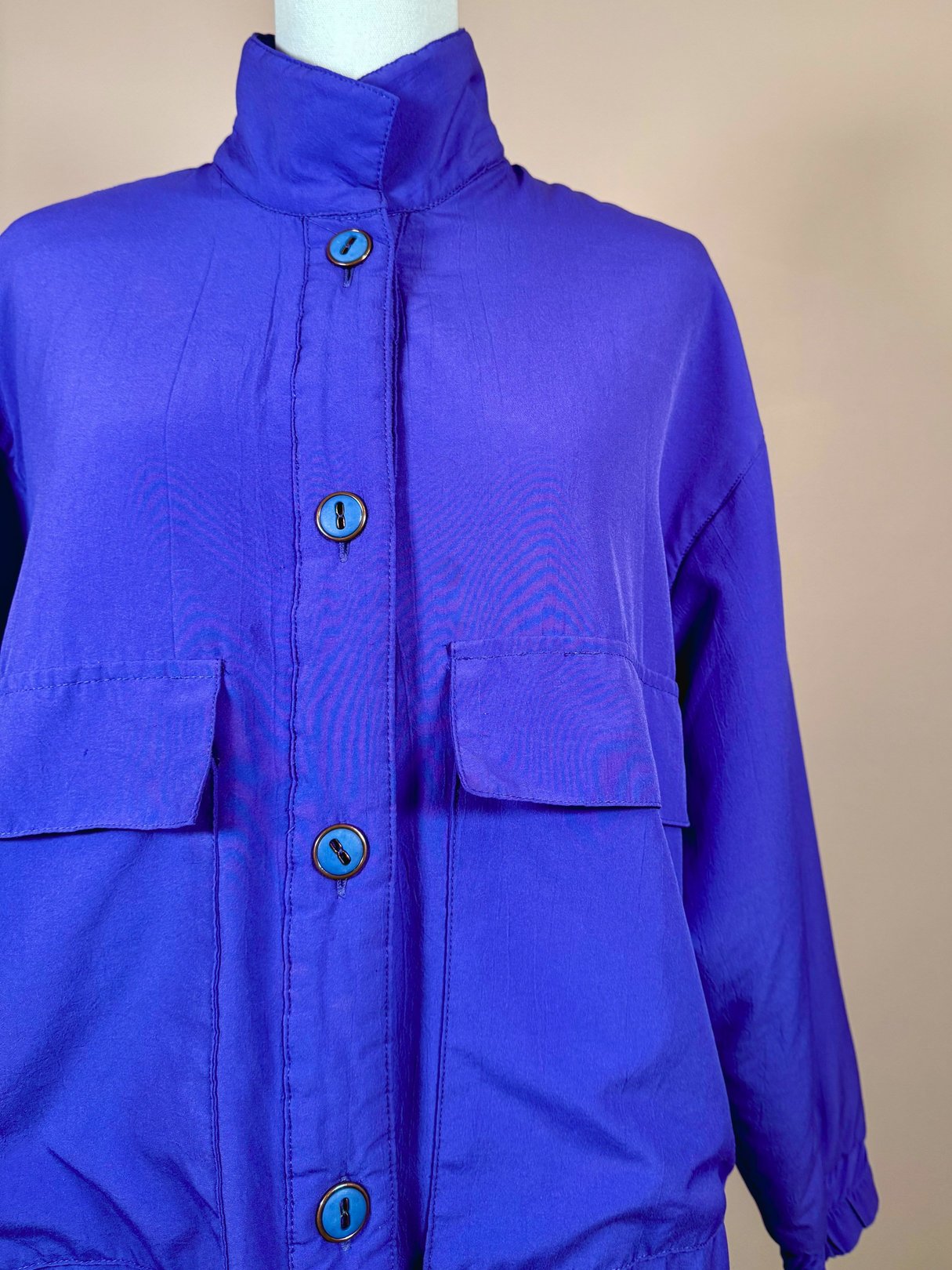 Vibrant violet women's jacket from the 1980s featuring a high collar, front buttons, and two chest pockets.