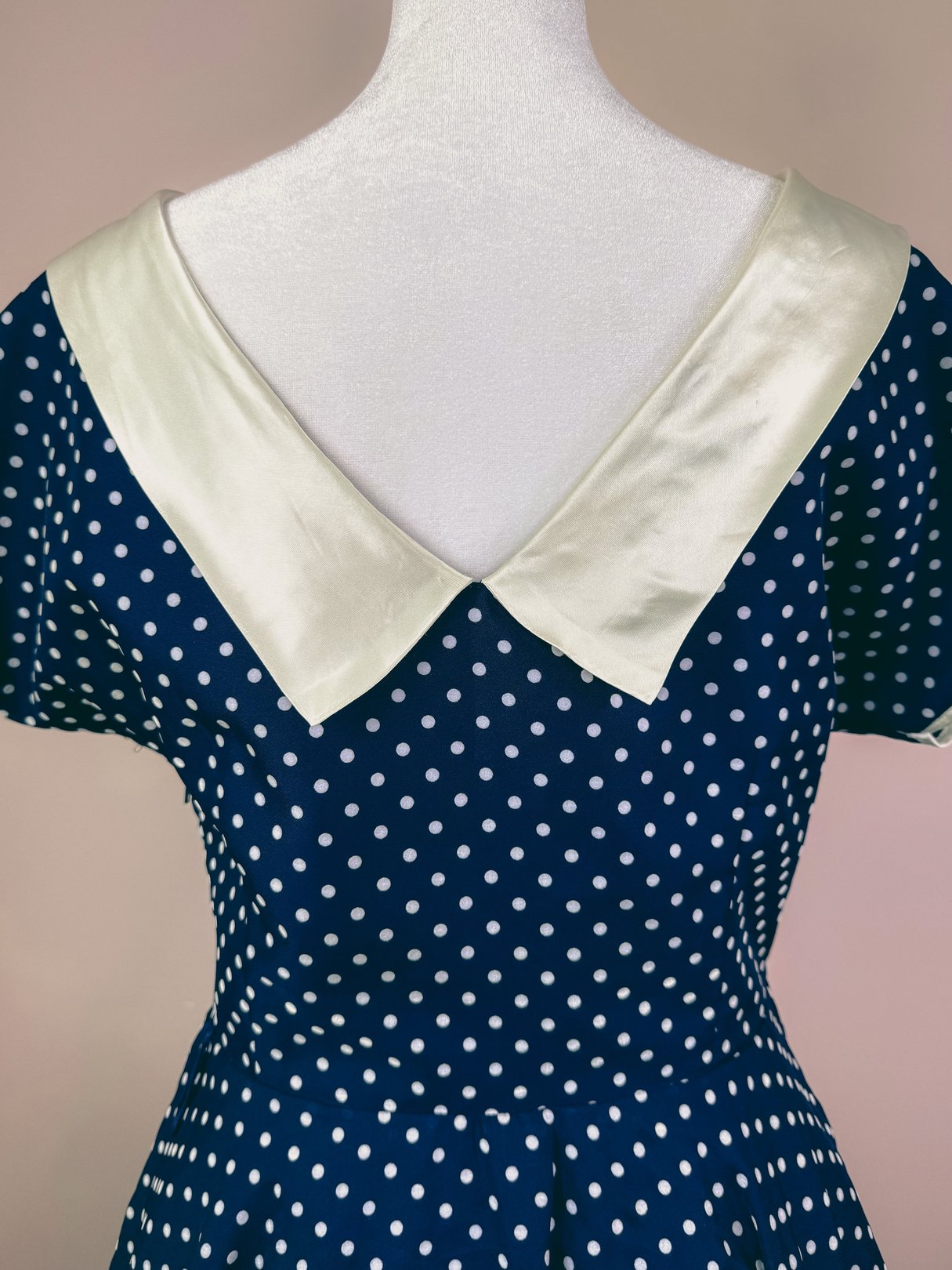 Navy blue 1950s women's dress featuring white polka dots and a satin finished collar.