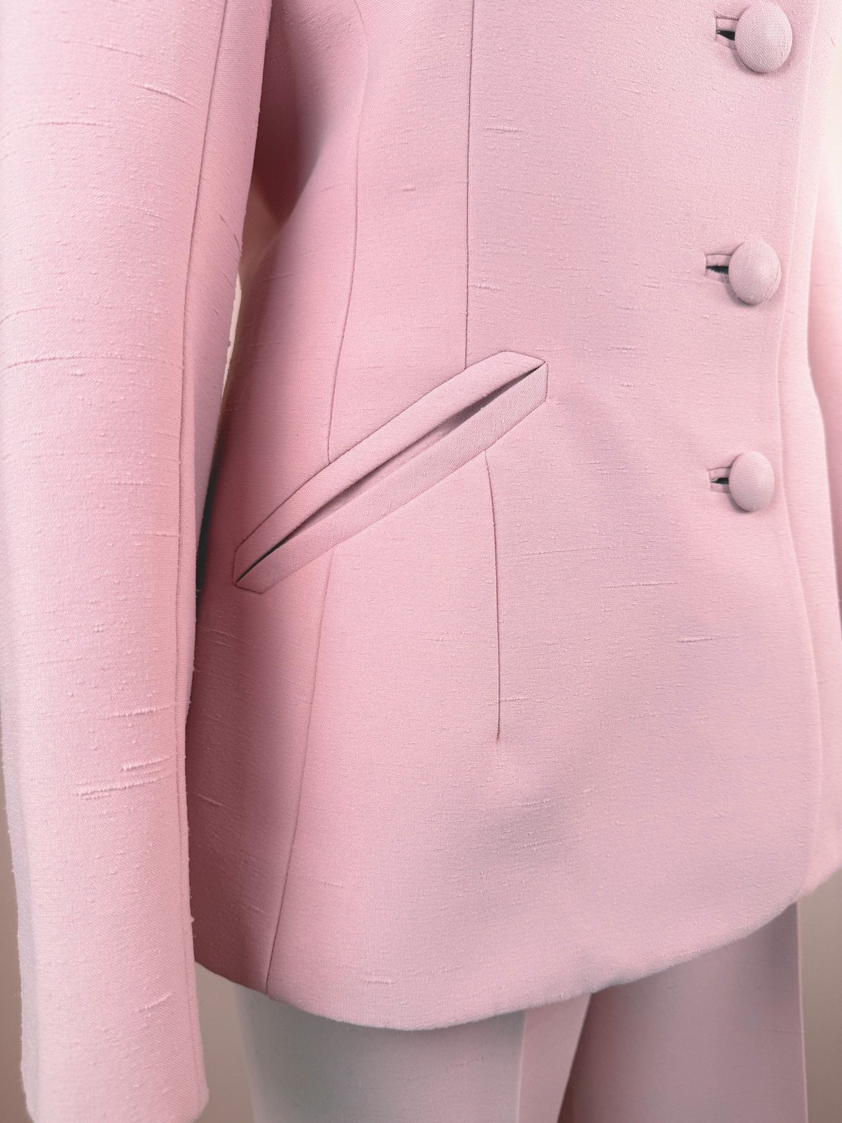 Blush pink 1970s women's three-piece suit featuring a tailored jacket with a single pocket and button details.
