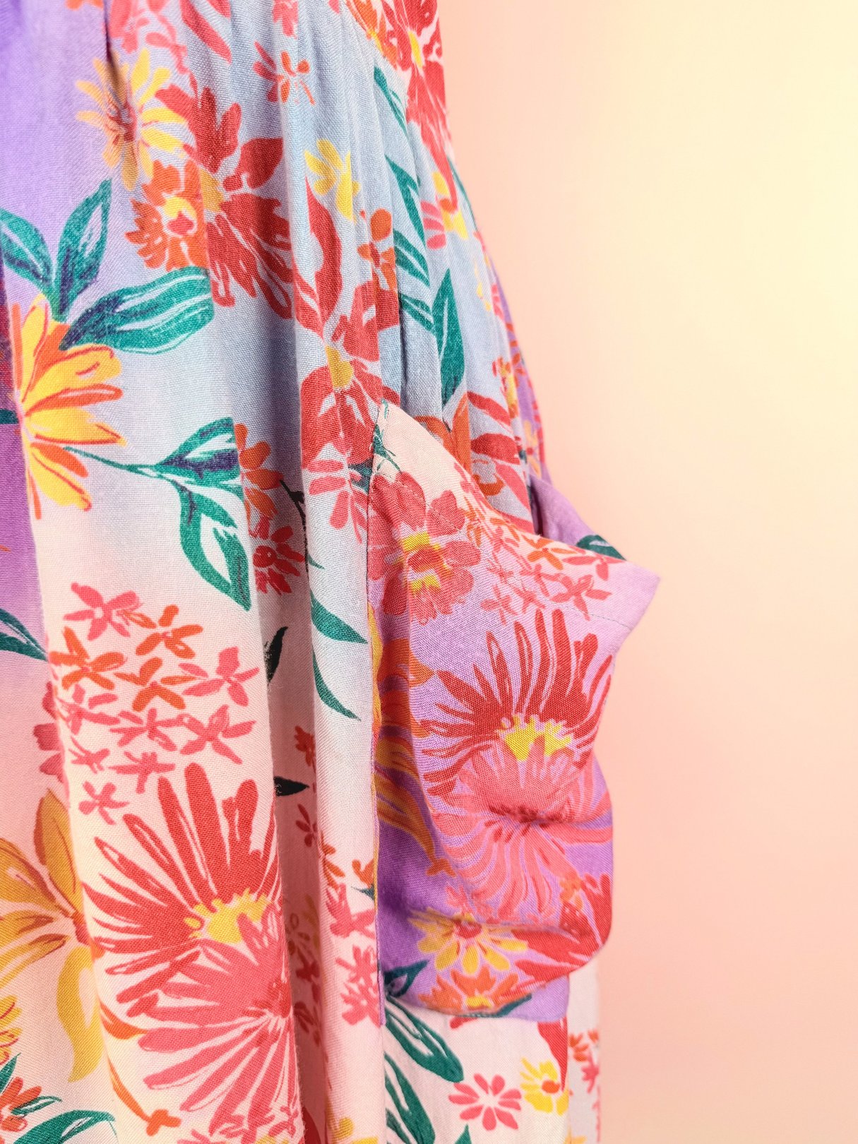 A pink 1990s summer dress featuring a vibrant floral pattern and a side pocket.