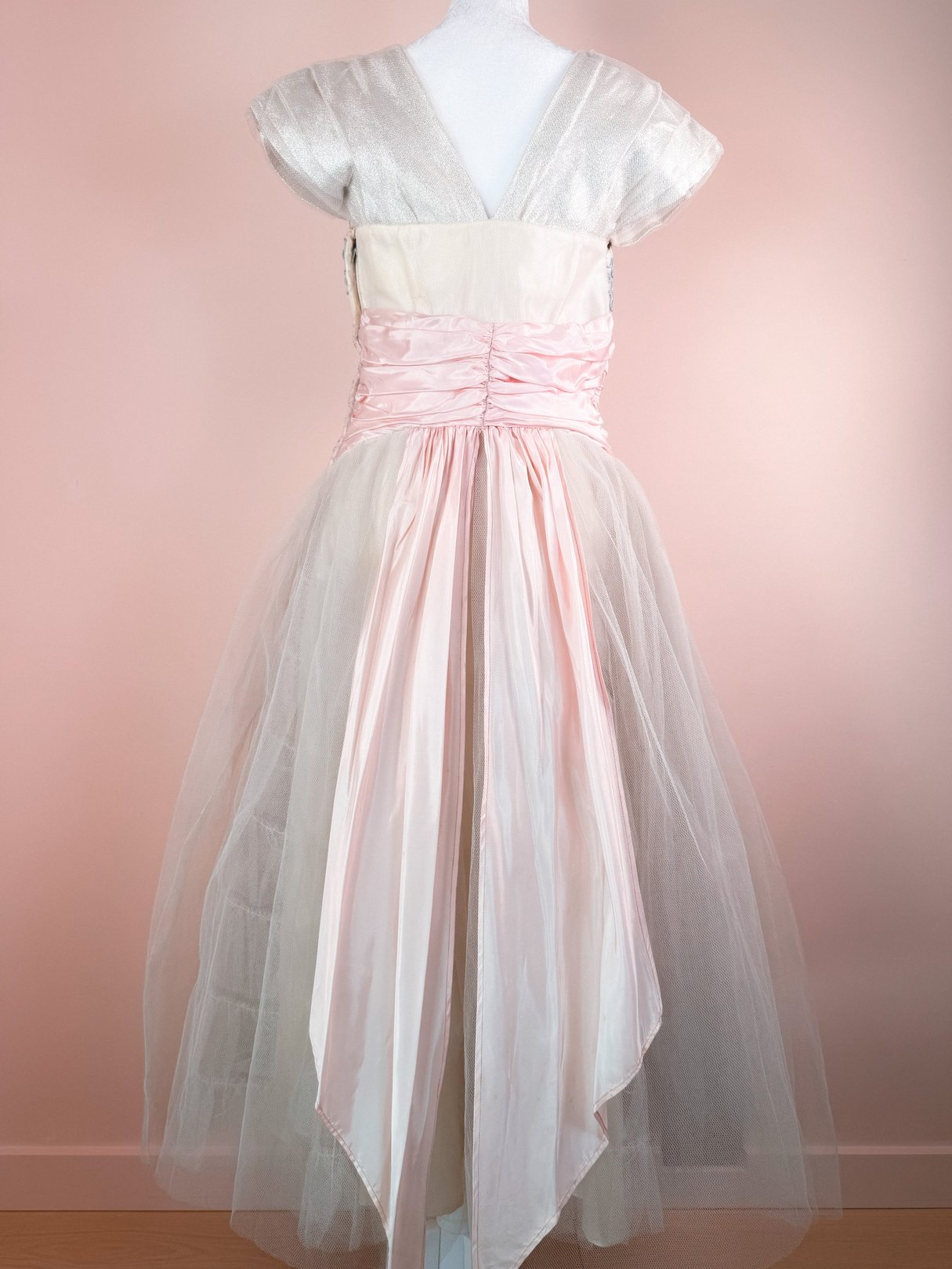 Silver 1950s women's dress with a fitted bodice, cap sleeves, and a pink satin sash at the waist, featuring a layered tulle skirt.