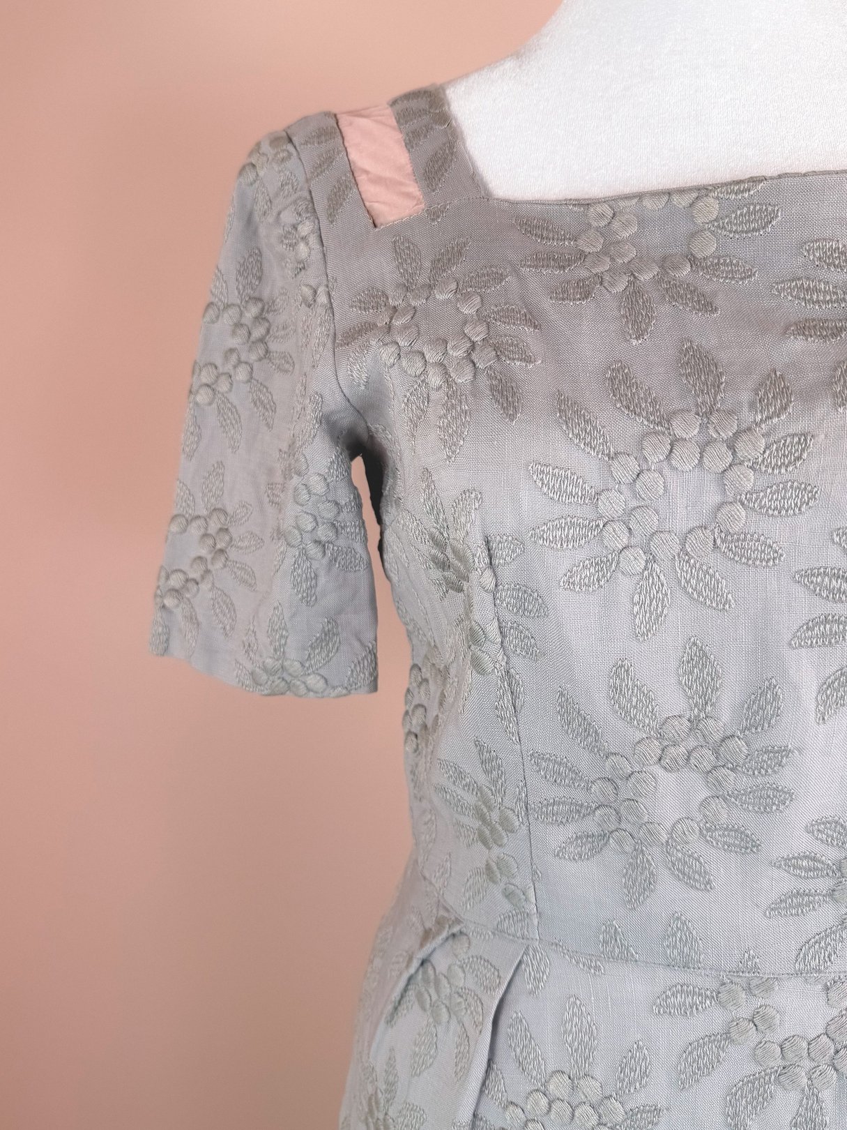 Slate blue 1950s women's dress featuring embroidered floral patterns and short sleeves.