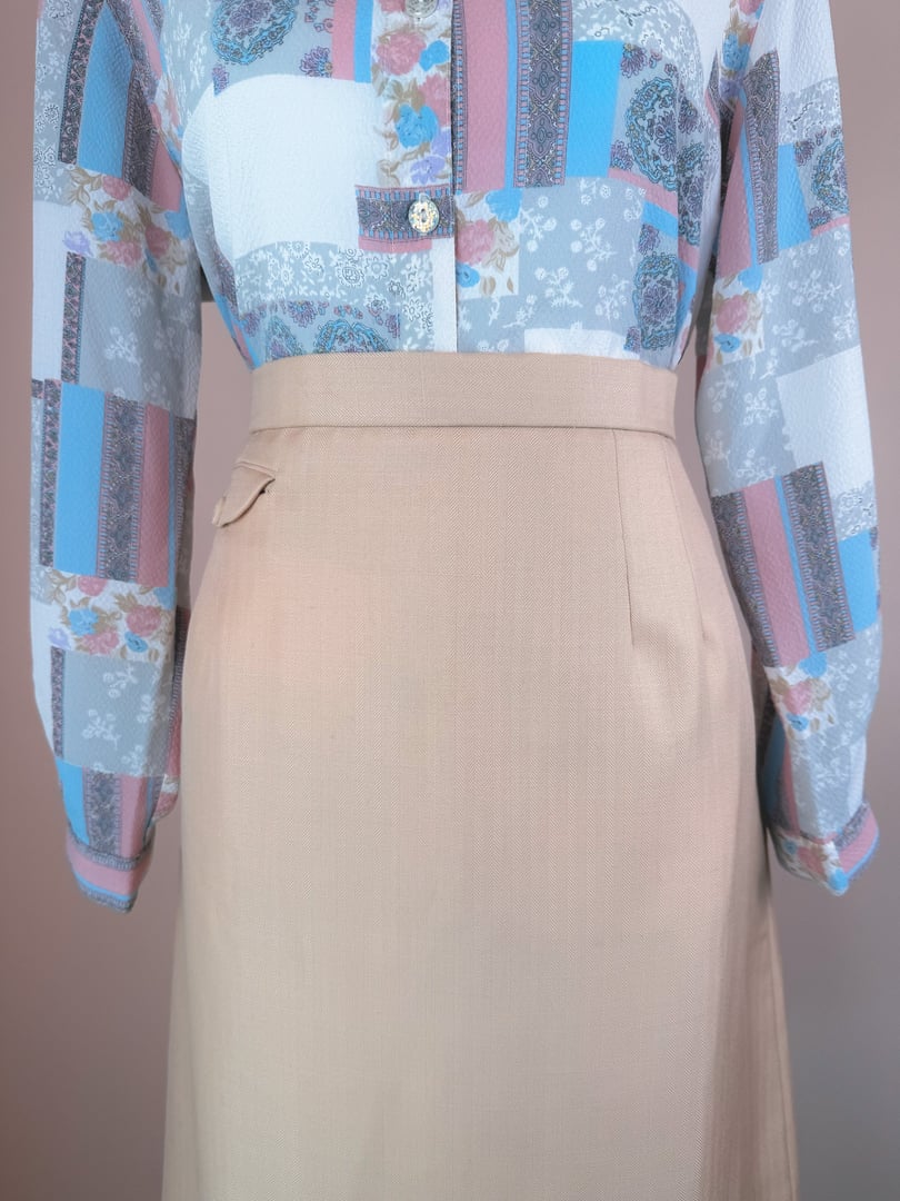 A cream beige women's skirt from the 1960s featuring a tailored fit and subtle detailing.