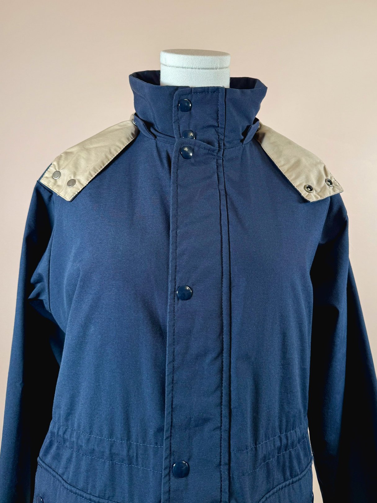 Navy blue women's utility field coat from the 1970s featuring beige snap-button shoulder accents.