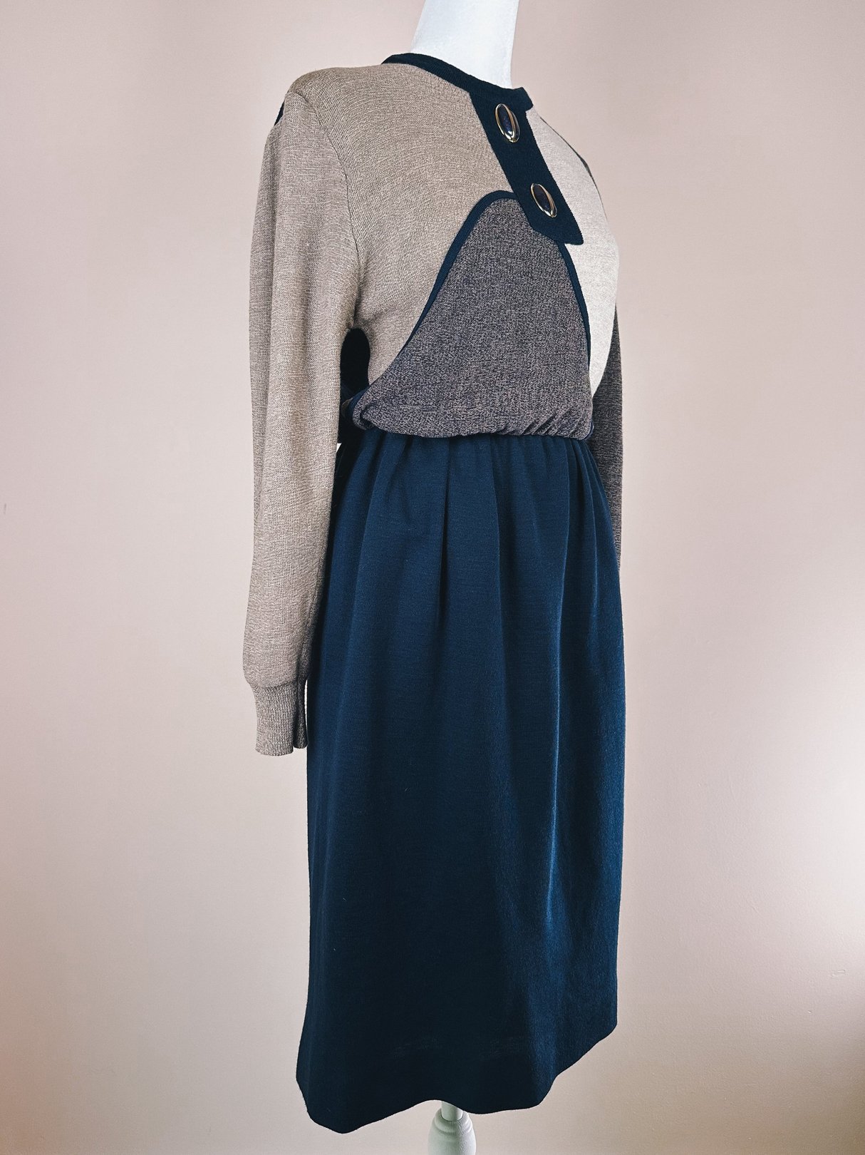 Navy blue 1980s women’s sweater dress featuring a contrasting top with button details and a cinched waist.