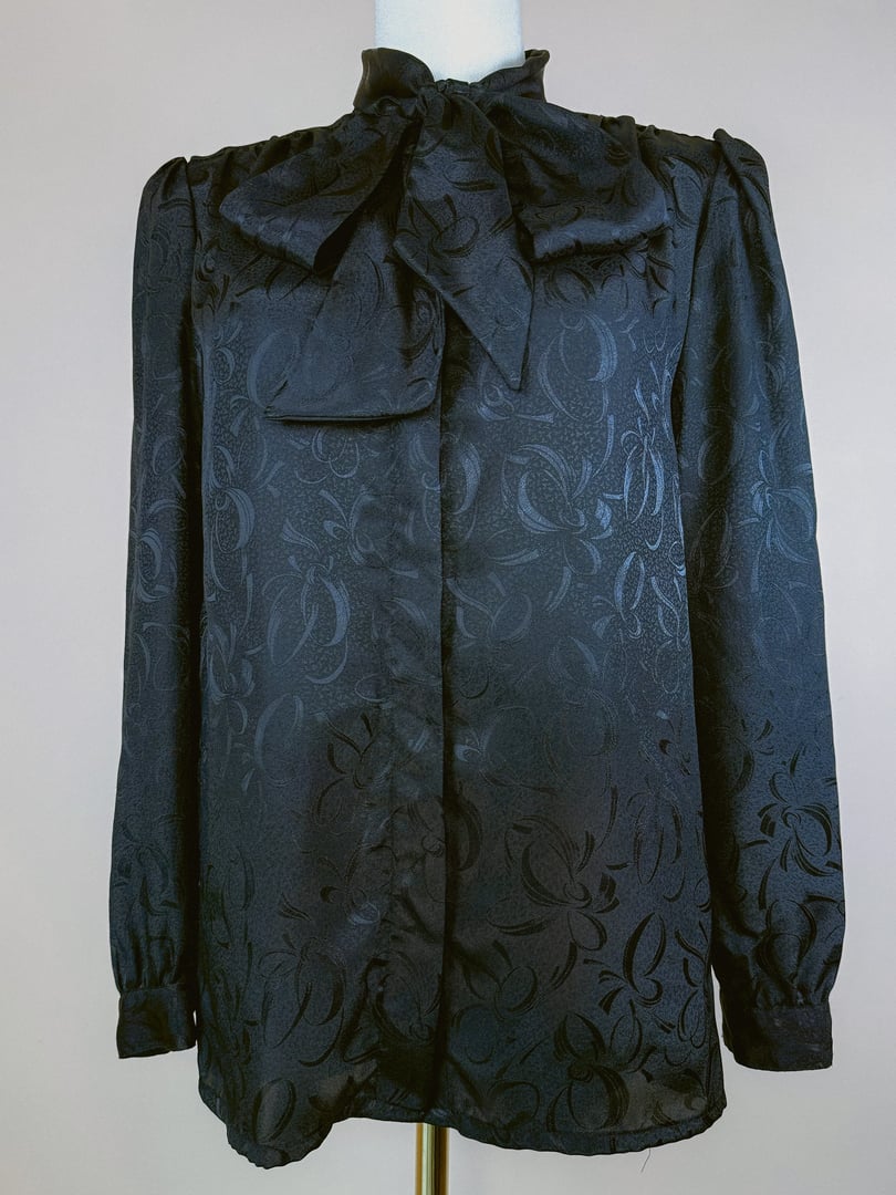 Black 1980s women's top featuring a bow tie neckline and a patterned fabric in black.