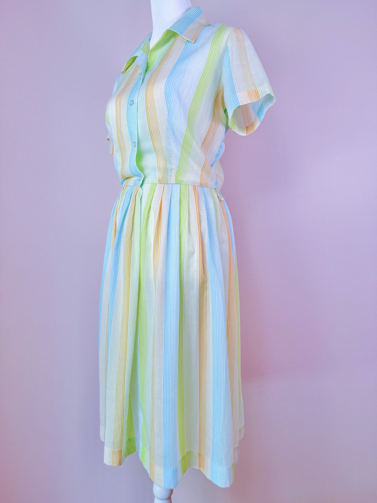 1950s women's Citrus Dress featuring vertical stripes in shades of orange, yellow, and green with a button-up front and short sleeves.