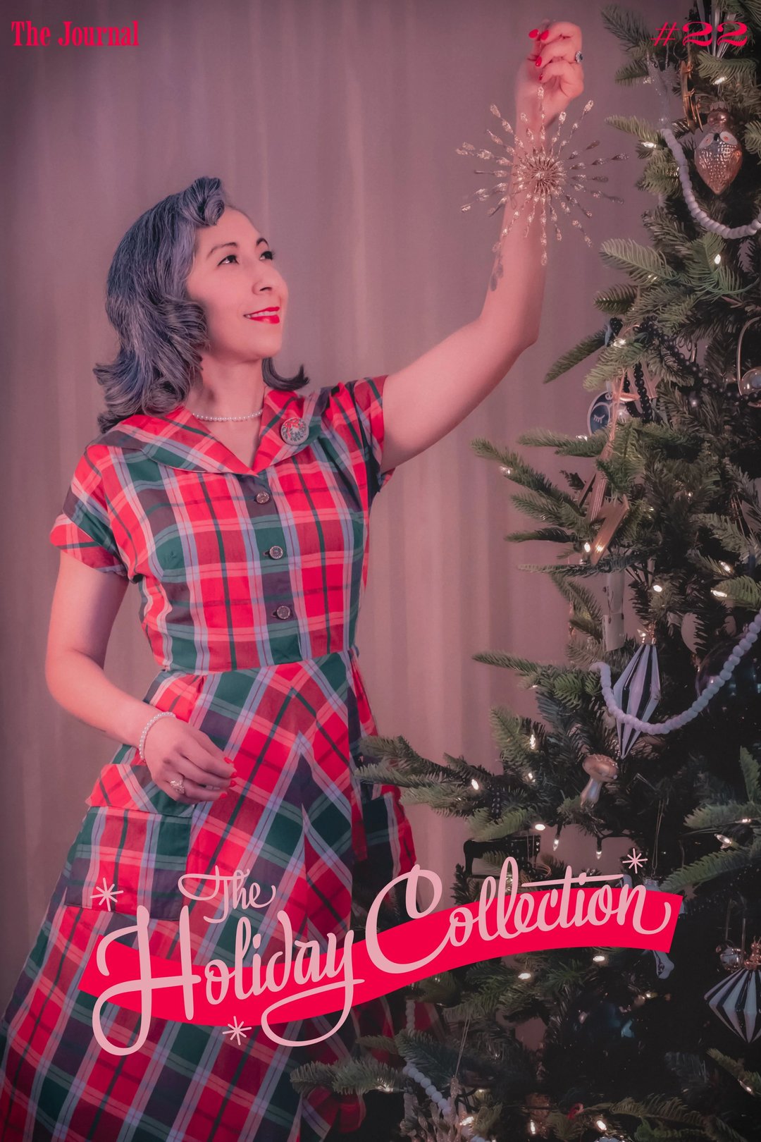 A woman in a plaid dress decorates a Christmas tree with ornaments and lights.