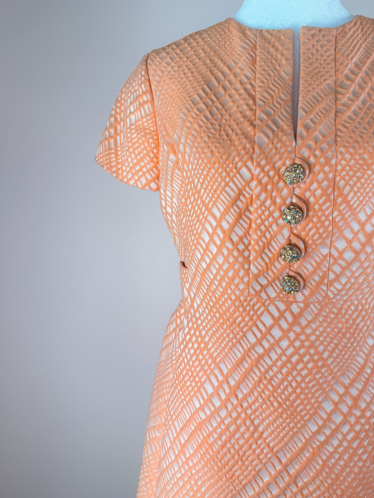 Orange 1960s dress featuring a textured pattern and four decorative buttons on the front.