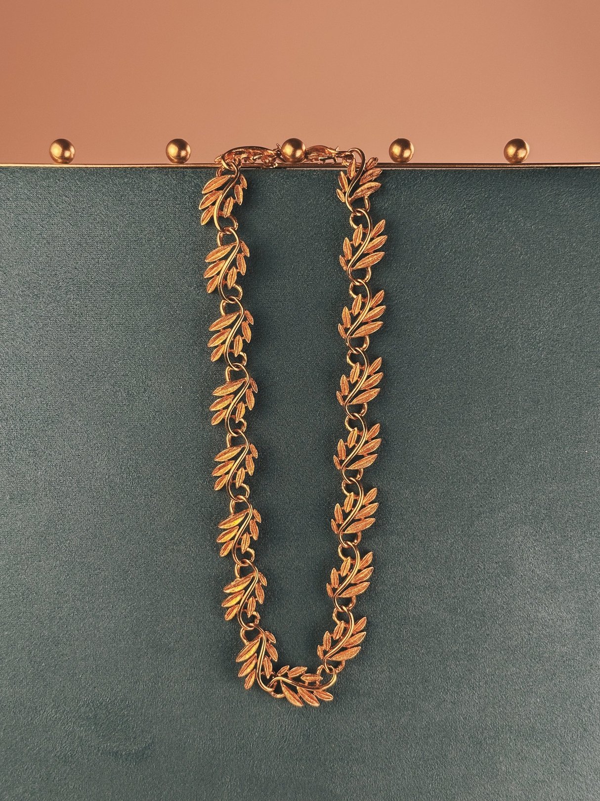 Gold tone collar necklace featuring swirled vine designs, designed for women in the 1970s.