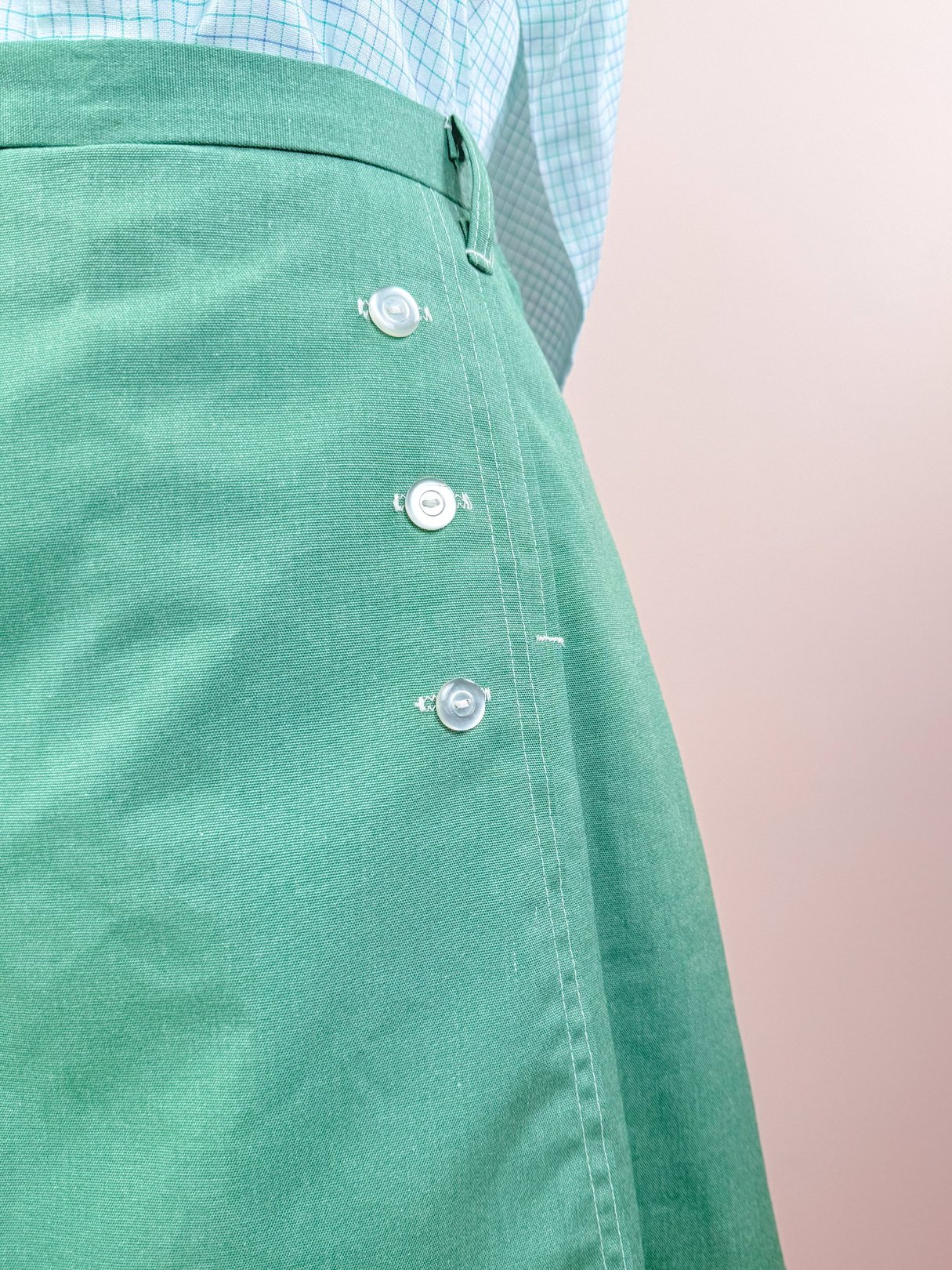 A green 1970s women's skort featuring decorative buttons on the side.