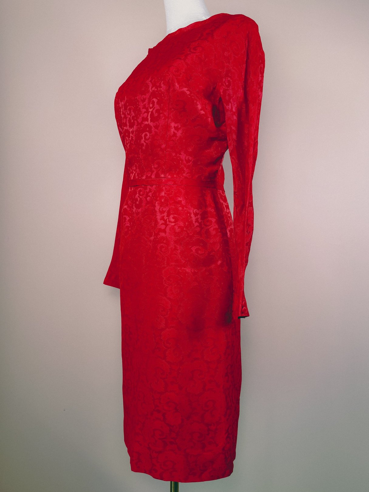 Red damask dress with long sleeves and a fitted silhouette, styled for women in the 1950s.