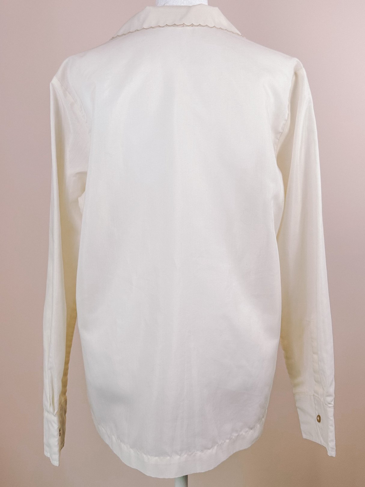 Cream-colored long-sleeve blouse with a scalloped collar and button closures, showcasing a hand-embroidered design in a 1950s style.