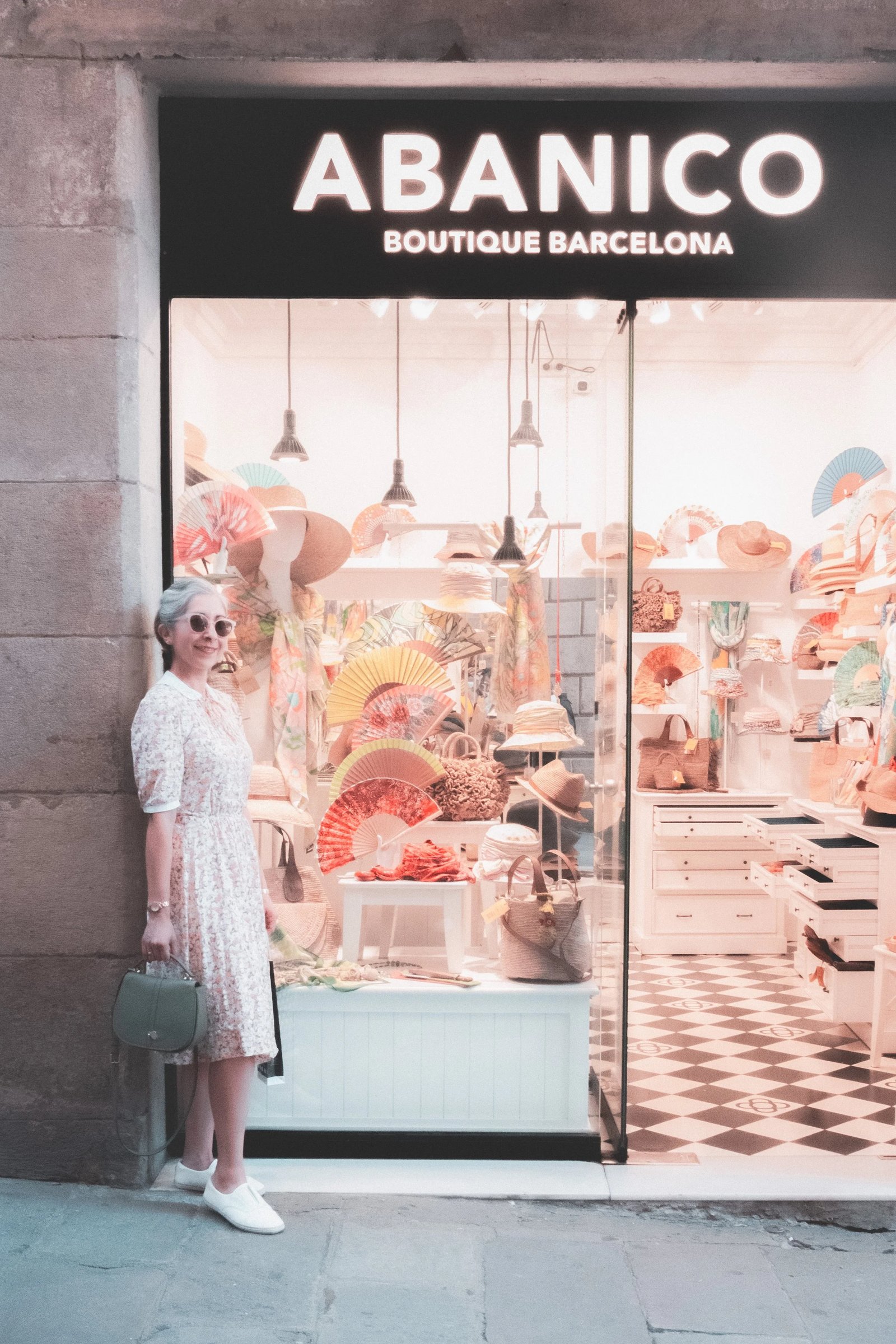 A woman in a white dress stands next to a colorful storefront displaying various decorative items.