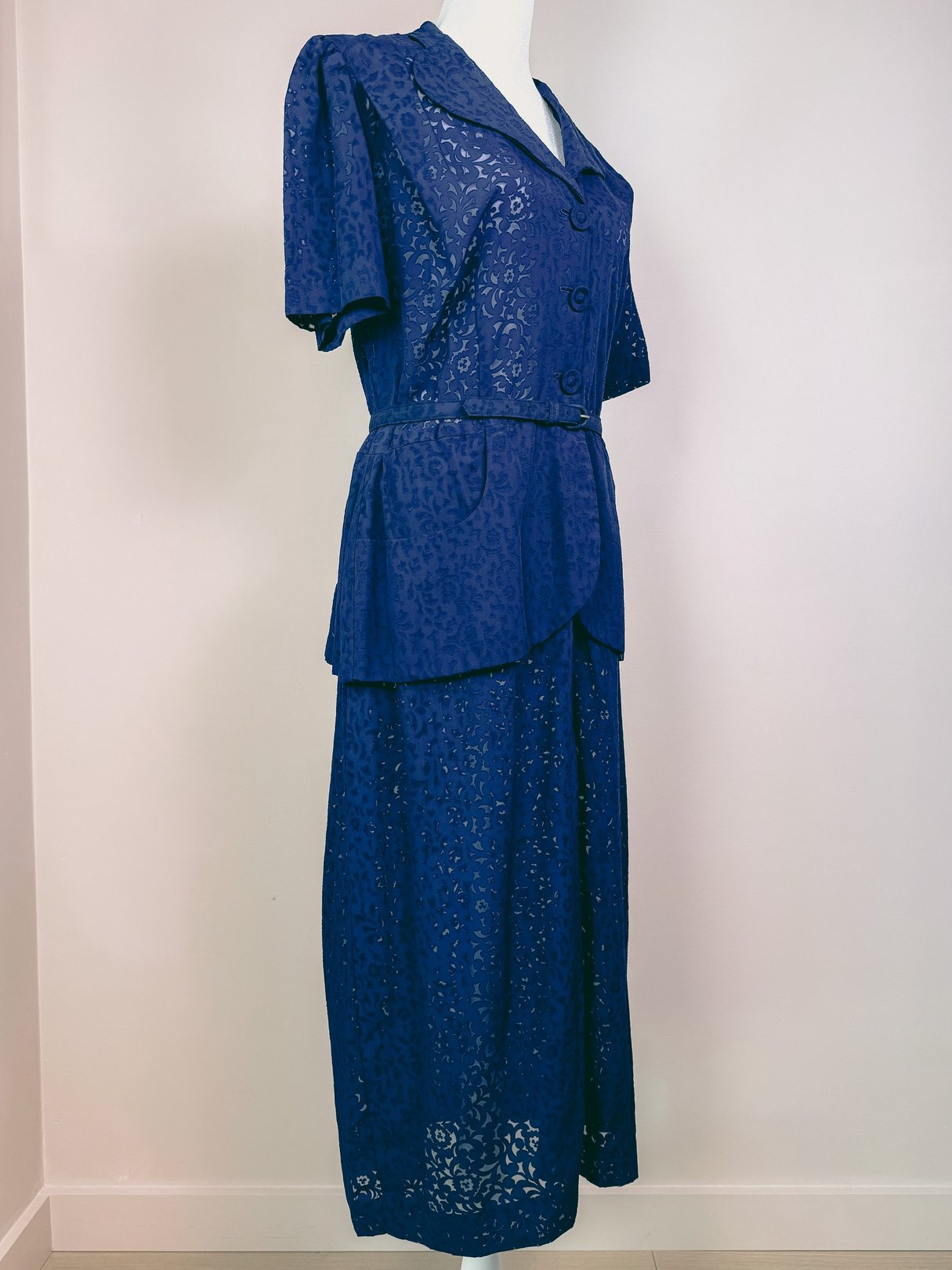 Navy blue women's dress from the 1940s featuring short sleeves, a fitted bodice, and a peplum waist.