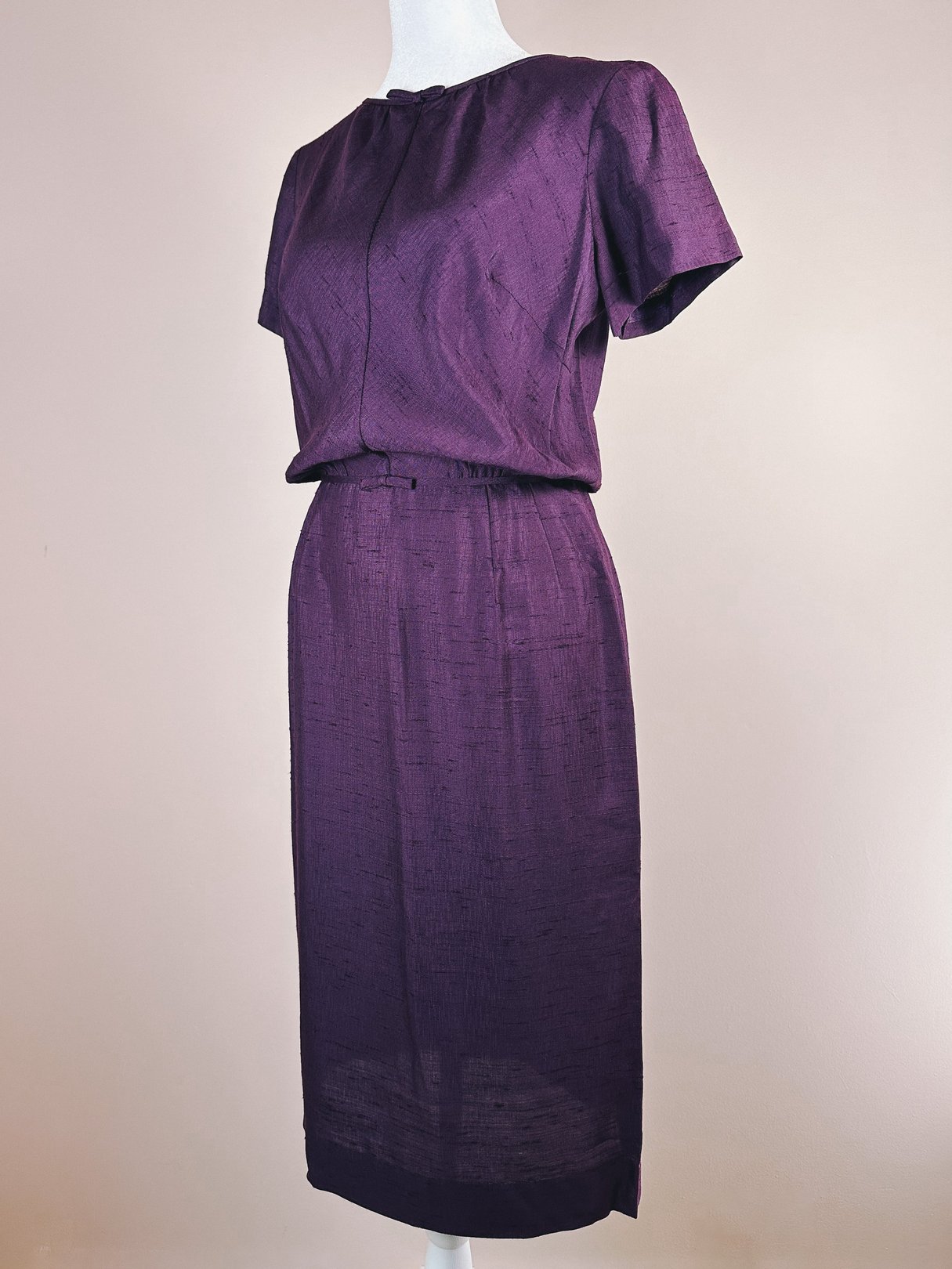 Purple 1960s women's dress featuring short sleeves and a bow detail on the front.