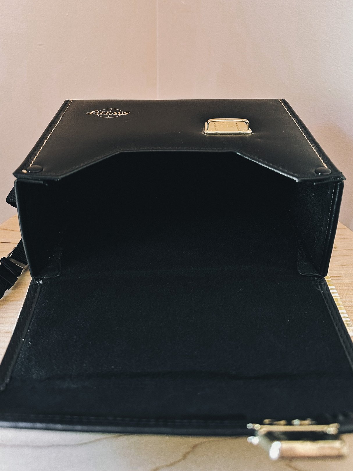 A 1970s black camera bag designed for women featuring a gold clasp and an open interior.