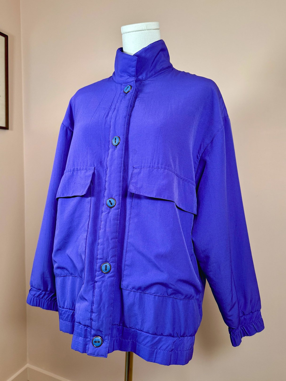 Vibrant violet women's jacket from the 1980s featuring a stand collar, two front pockets, and button closure.