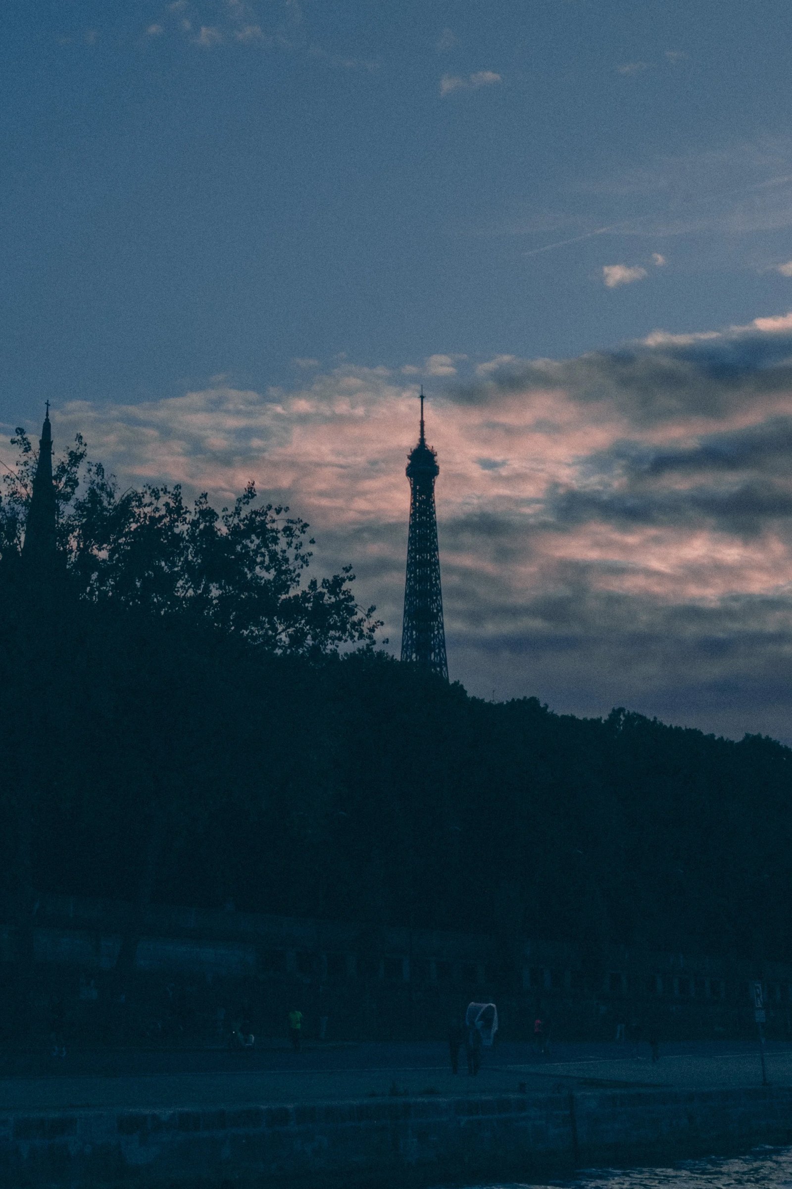 The silhouette of the Eiffel Tower against a dramatic sky at dusk.