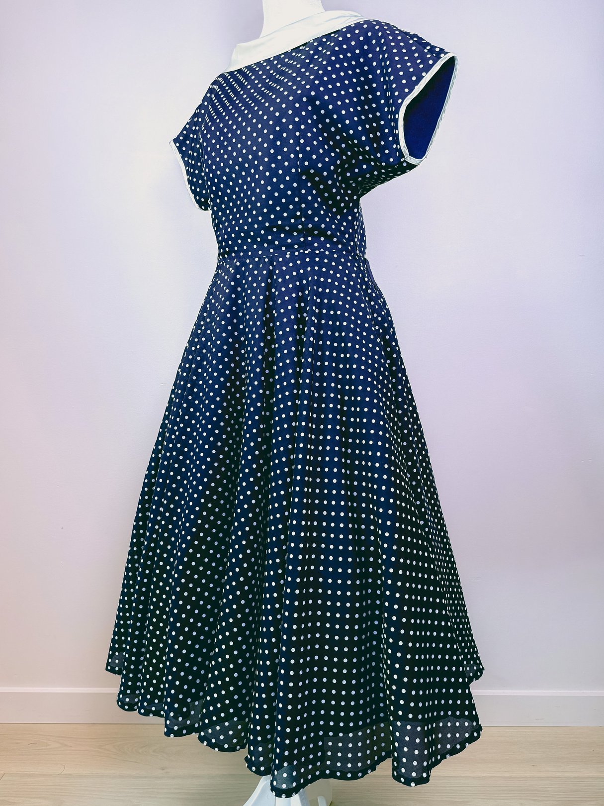 Navy blue 1950s-style women's dress with white polka dots and a flared skirt.