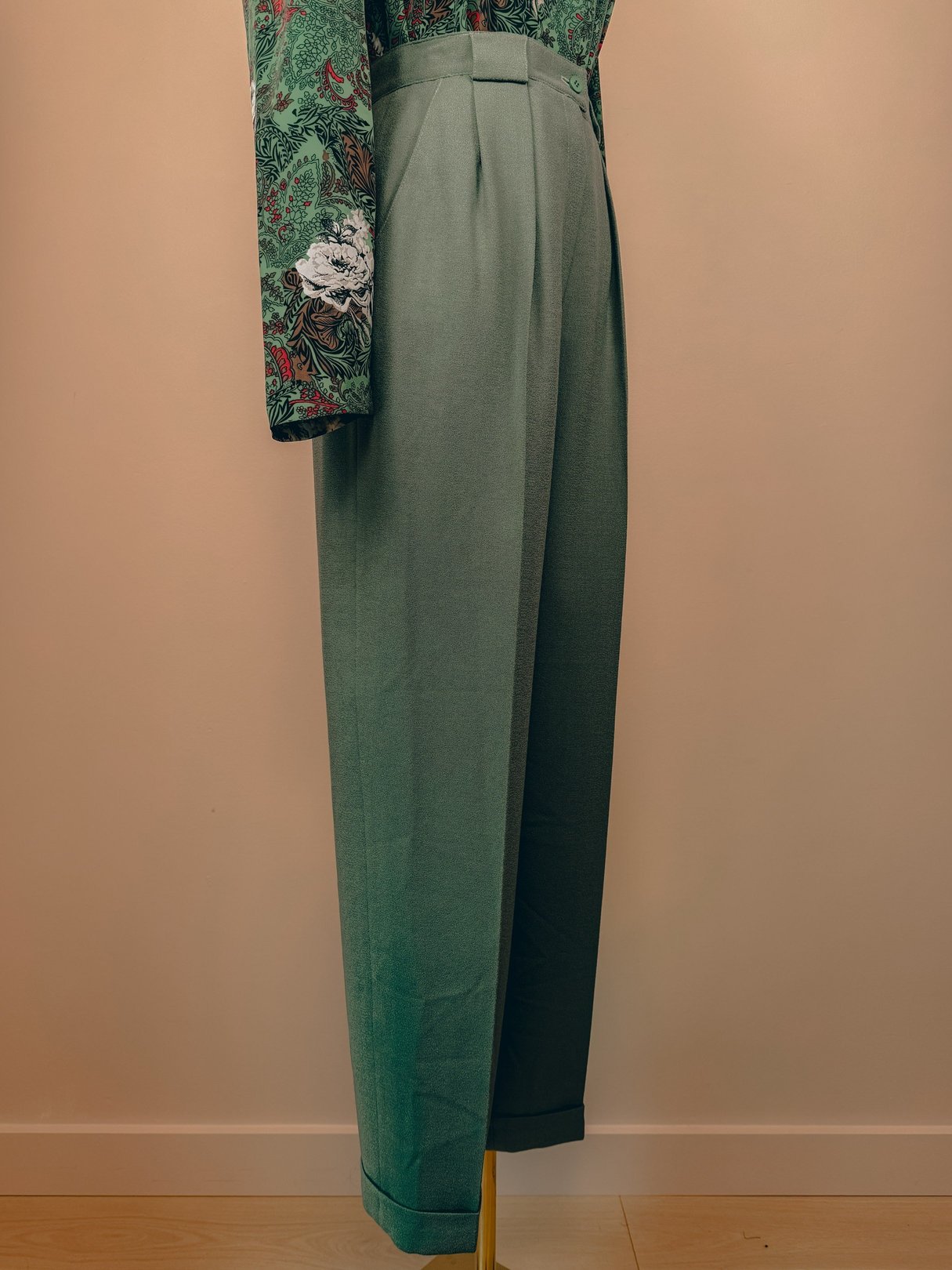 Sage green pleated trousers for women, styled in the 1980s with a relaxed fit and cuffed hems.