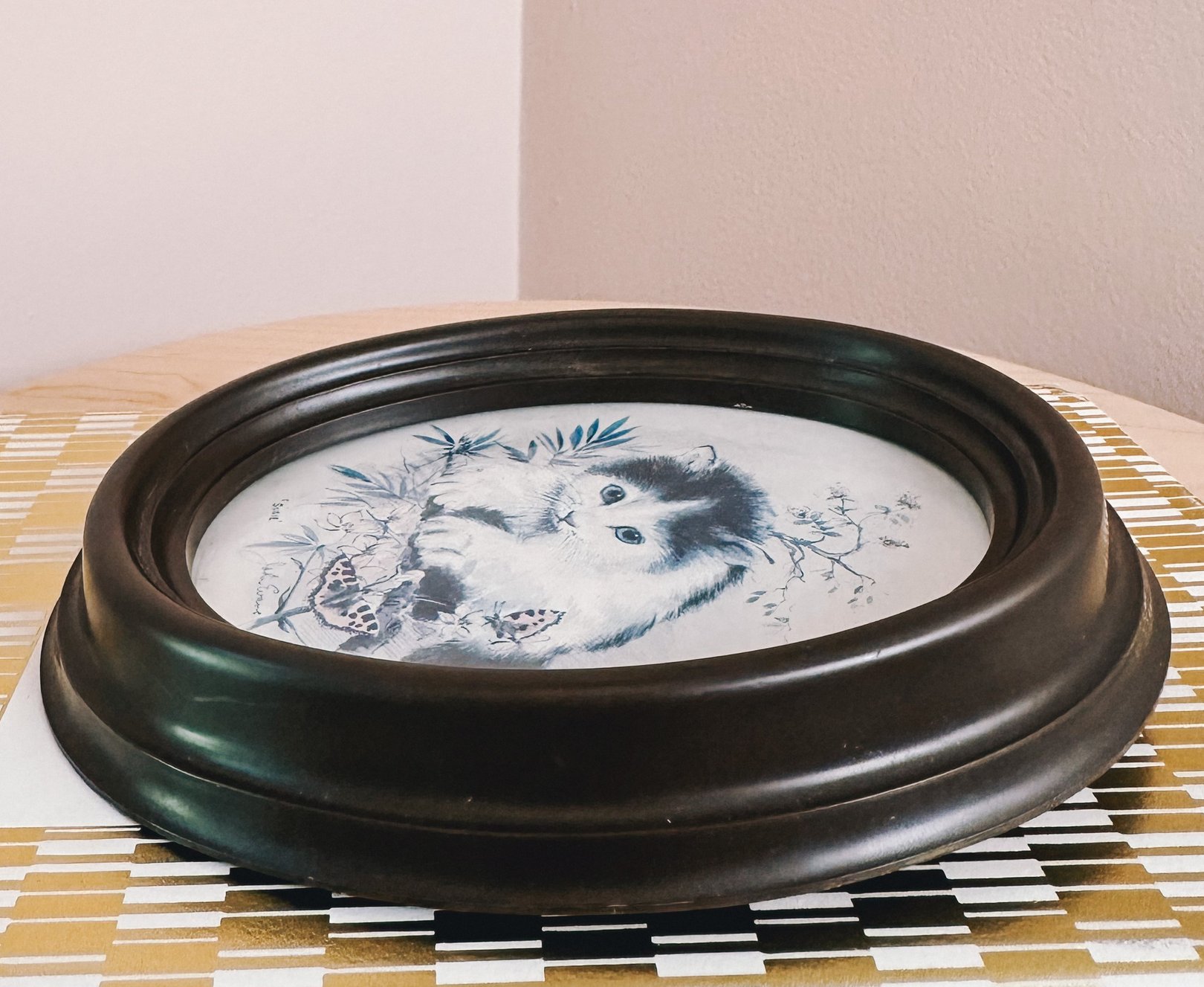 Framed 1970s portrait of a blue and white cat resting among floral elements, suitable for home decor.