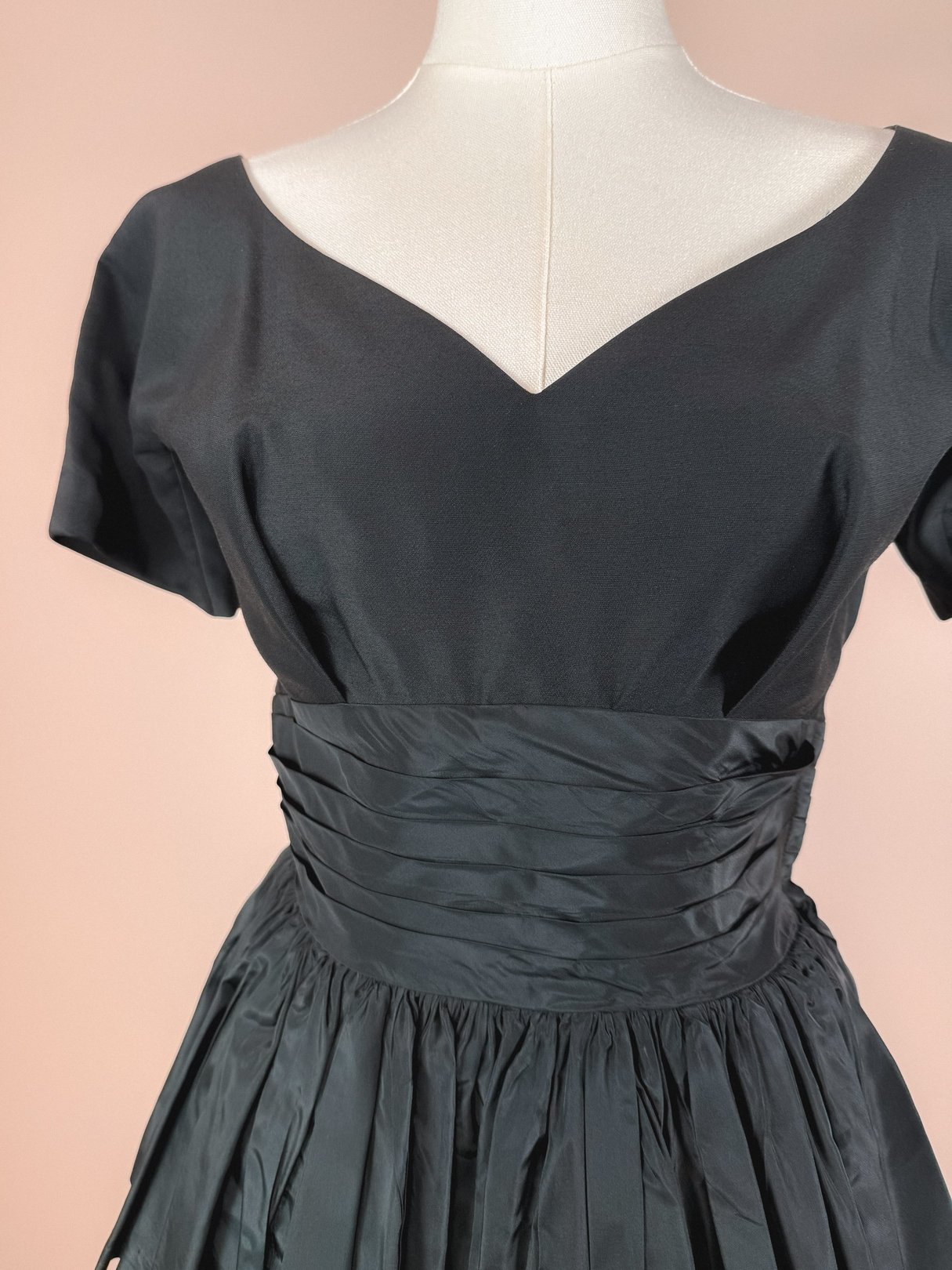 Black 1950s-style women's dress with a fitted bodice and pleated skirt.