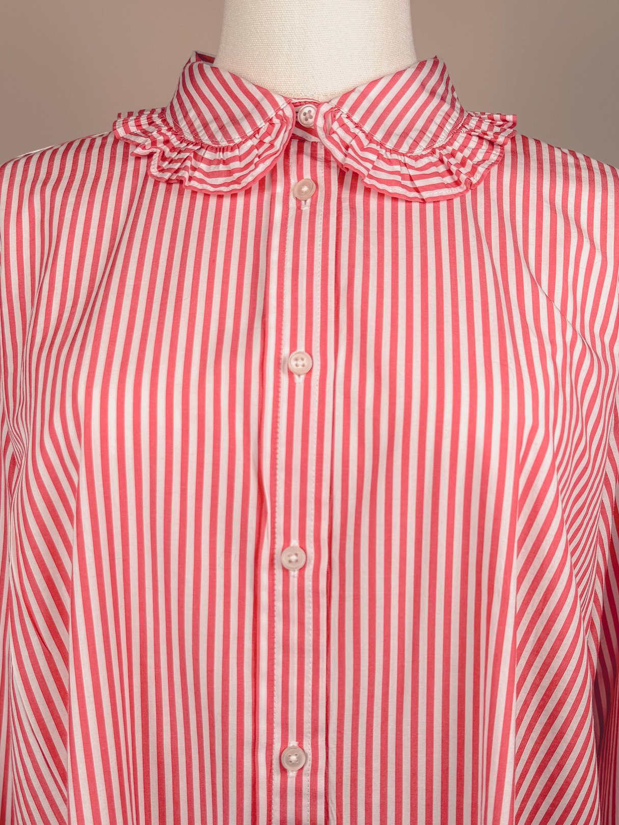 Red and white striped button-down top with a ruffled collar, designed for women and reflecting a 1970s style.