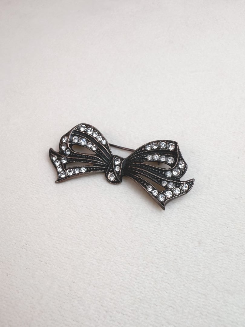 Silver 1970s-inspired Deco Bow Pin adorned with sparkling rhinestones.