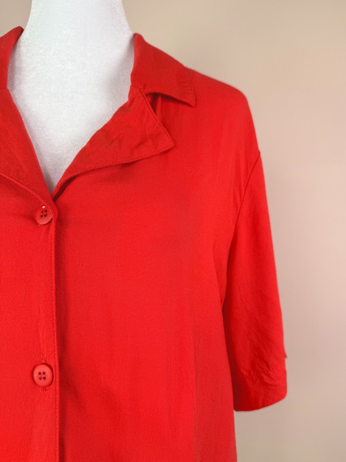 Red 1980s women's top featuring a collared neckline and short sleeves with two buttons.
