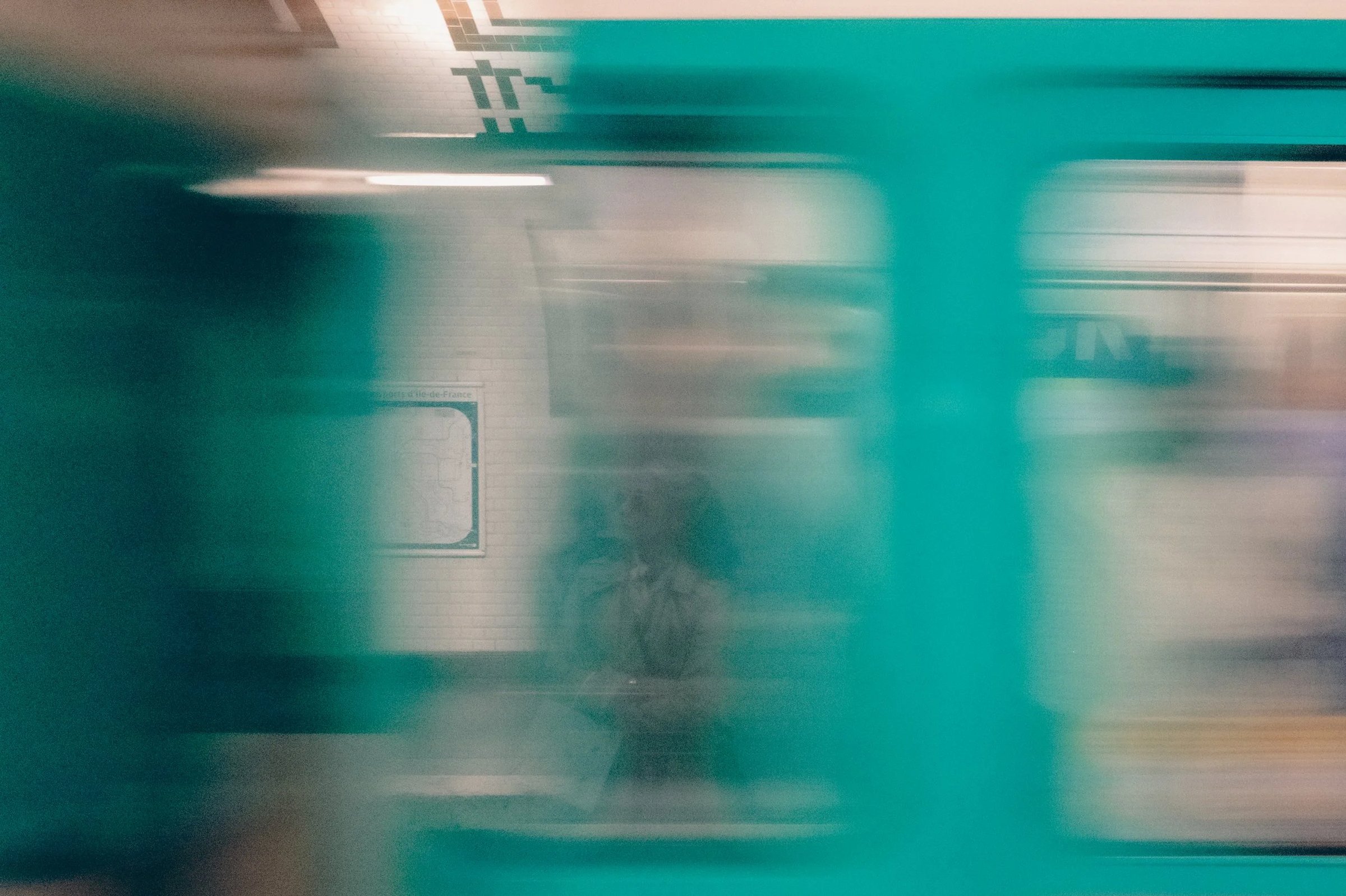 A blurred view of a subway station with a person standing on the platform.