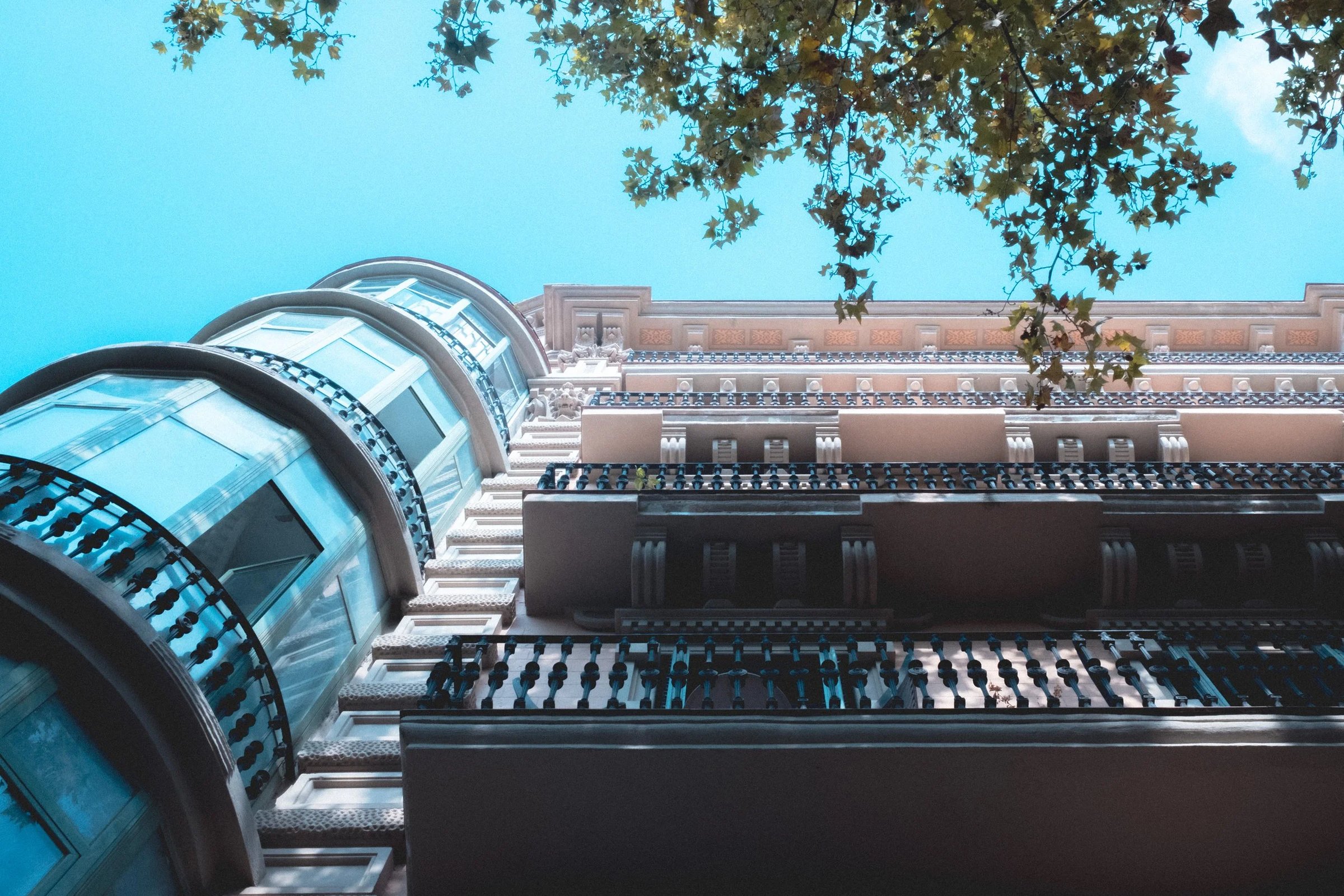 A low-angle view of a decorative building facade featuring balconies and large windows under a clear blue sky.