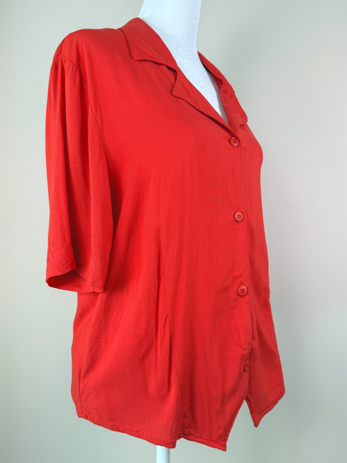 Red 1980s-style women's top with a collared neckline and short sleeves featuring button closures.