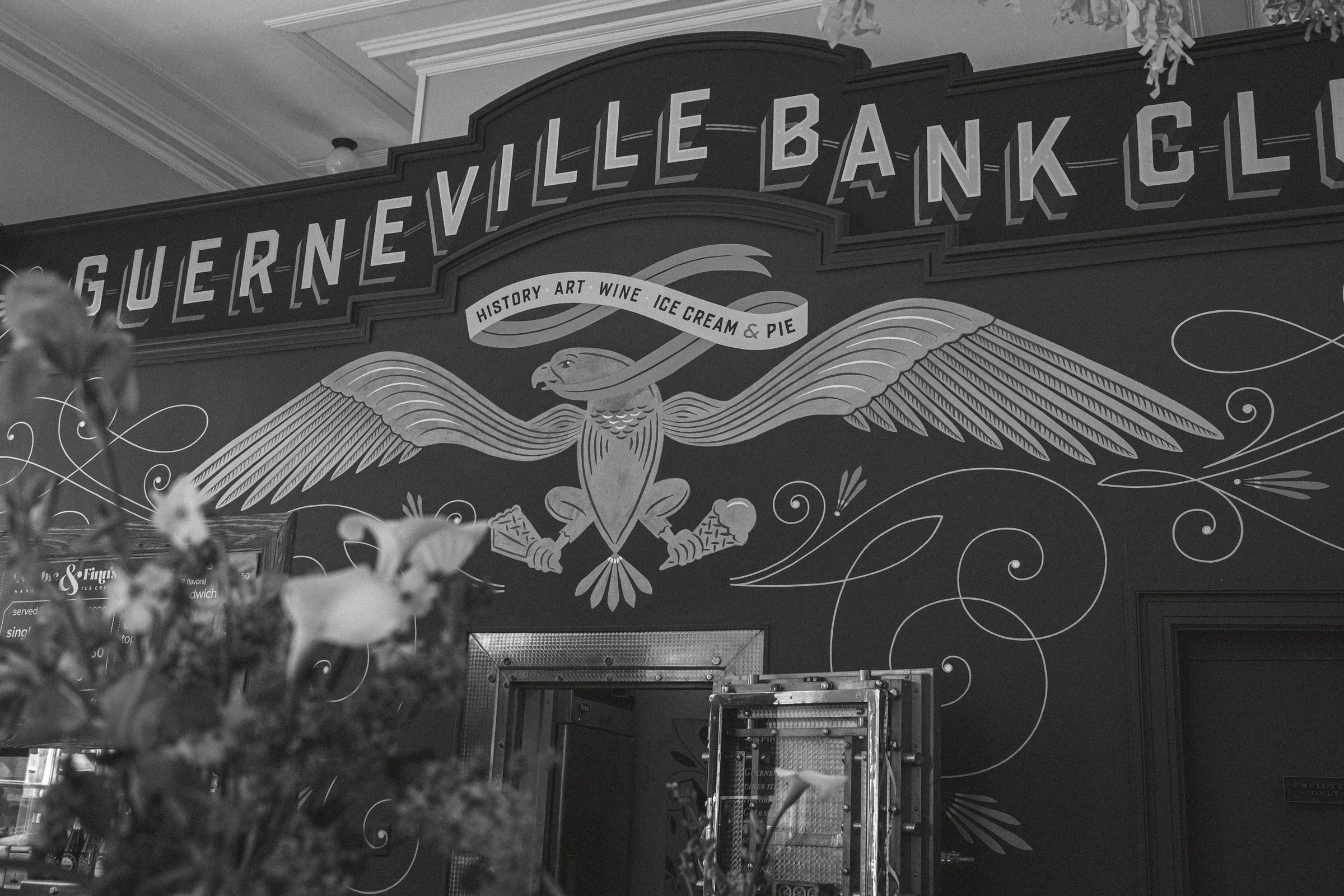 A decorative mural featuring an eagle and the text "Nevi lle Bank" alongside the words "History, Art, Wine, Ice Cream & Pie.