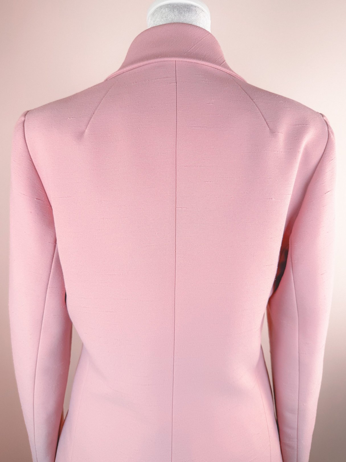 Blush pink women's suit jacket from the 1970s with a fitted silhouette and high collar.