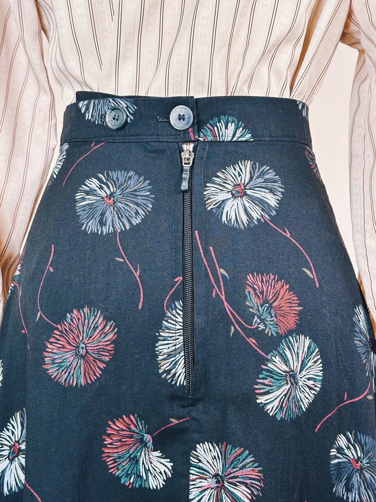 Black Dandelion Ruffle Skirt from the 1970s featuring a colorful floral pattern and a front zipper closure.