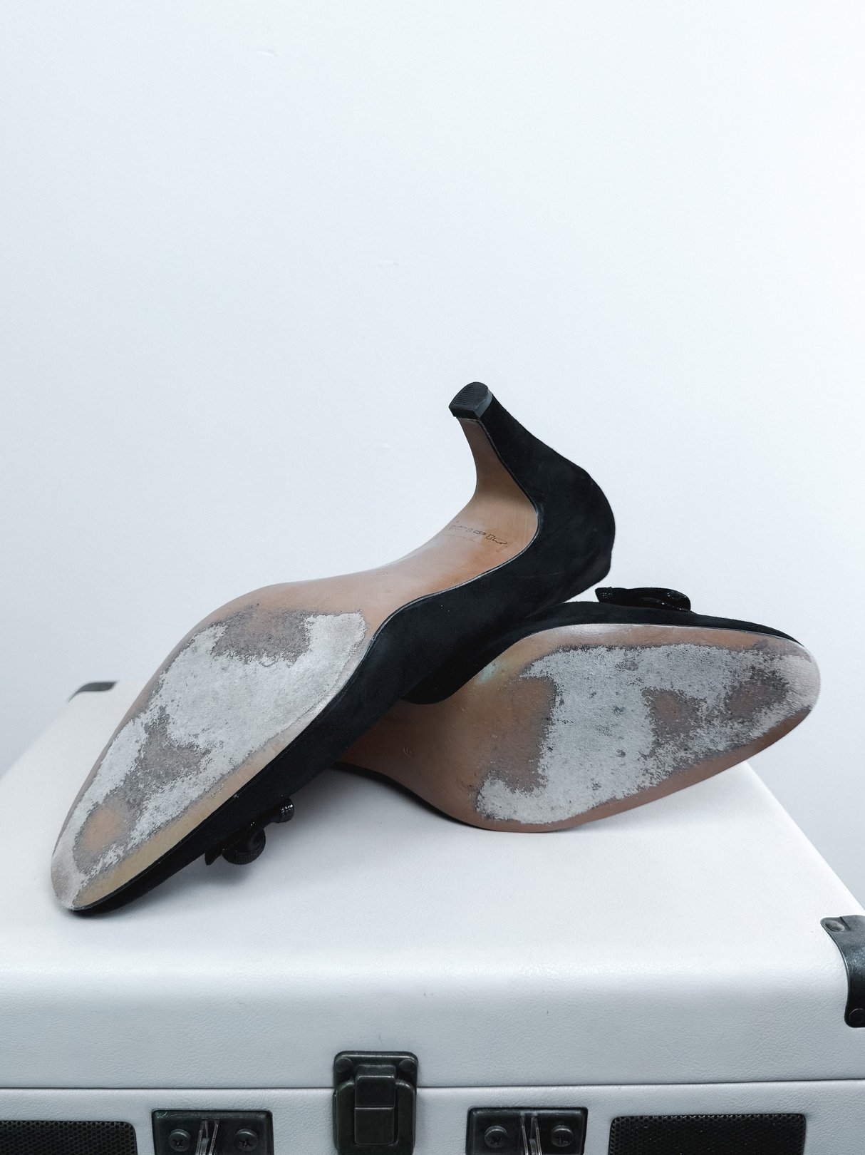 Black suede pumps with a pointed toe and a stiletto heel, showing signs of wear on the soles, indicative of 1970s style.