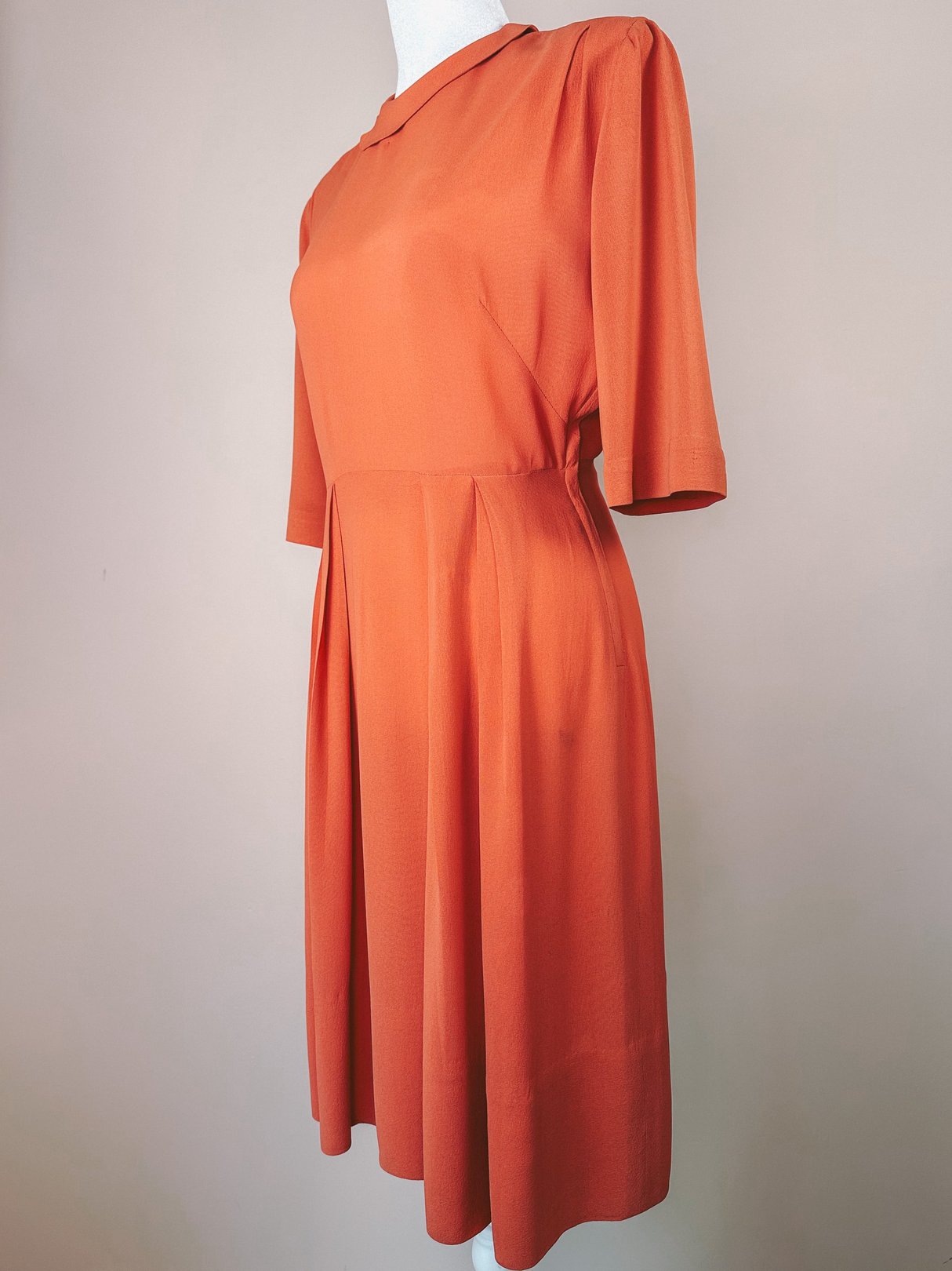 Coral 1940s-style women's dress with short puff sleeves and a flared skirt.