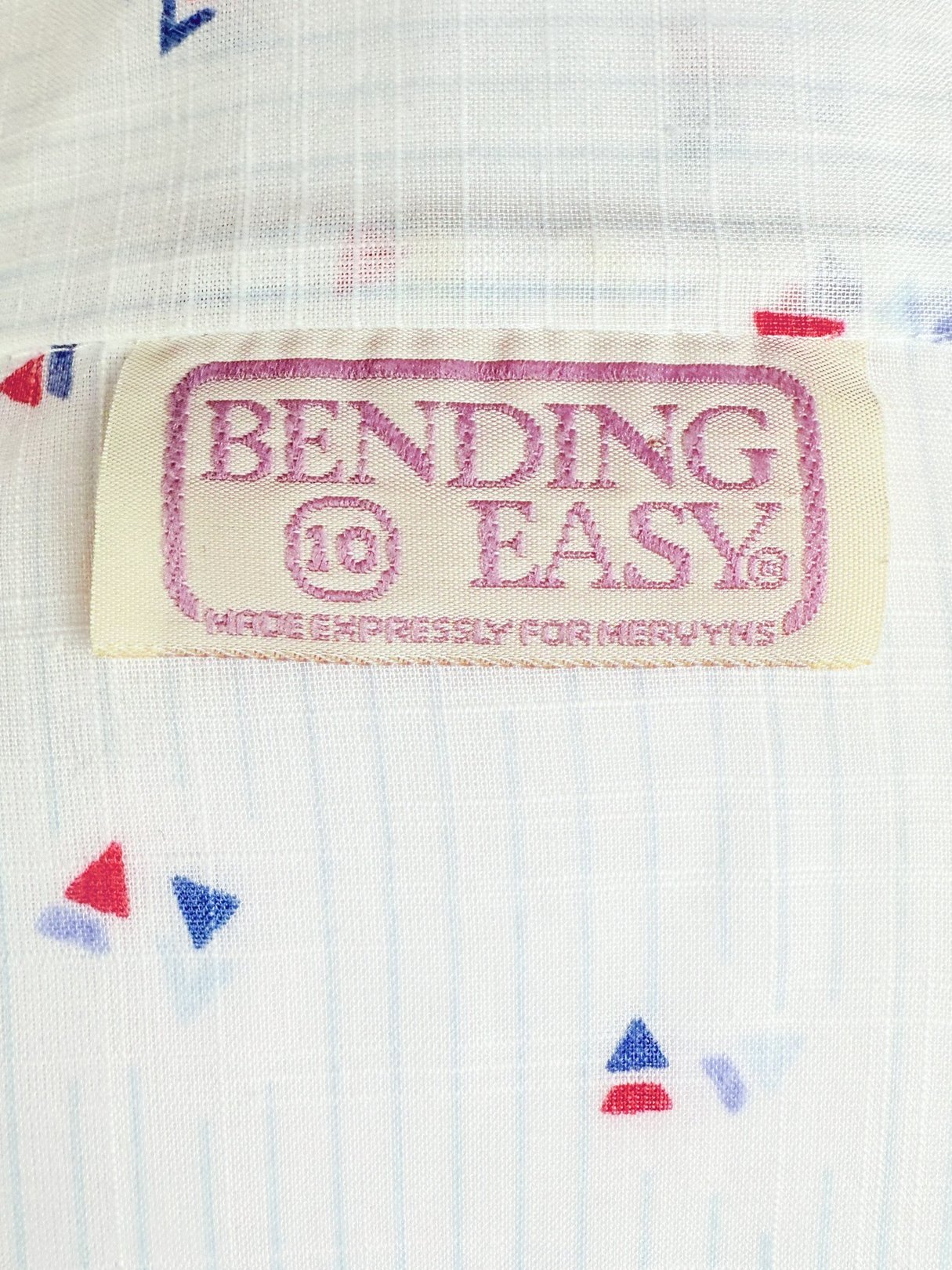 White top with a geometric pattern featuring blue and red triangular shapes, labeled 'BENDING EASY,' designed for women and dating from the 1980s.