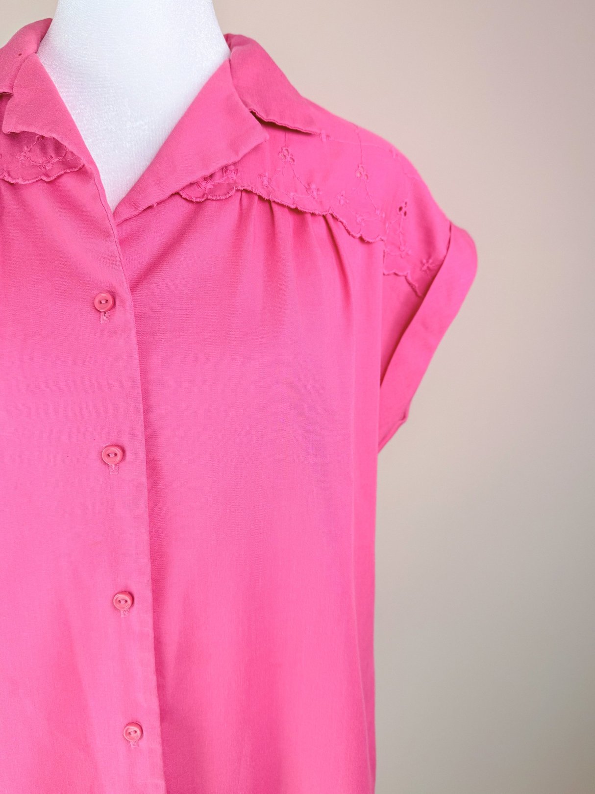 Pink sleeveless blouse with a button front and lace detailing on the collar, representing 1980s women's fashion.