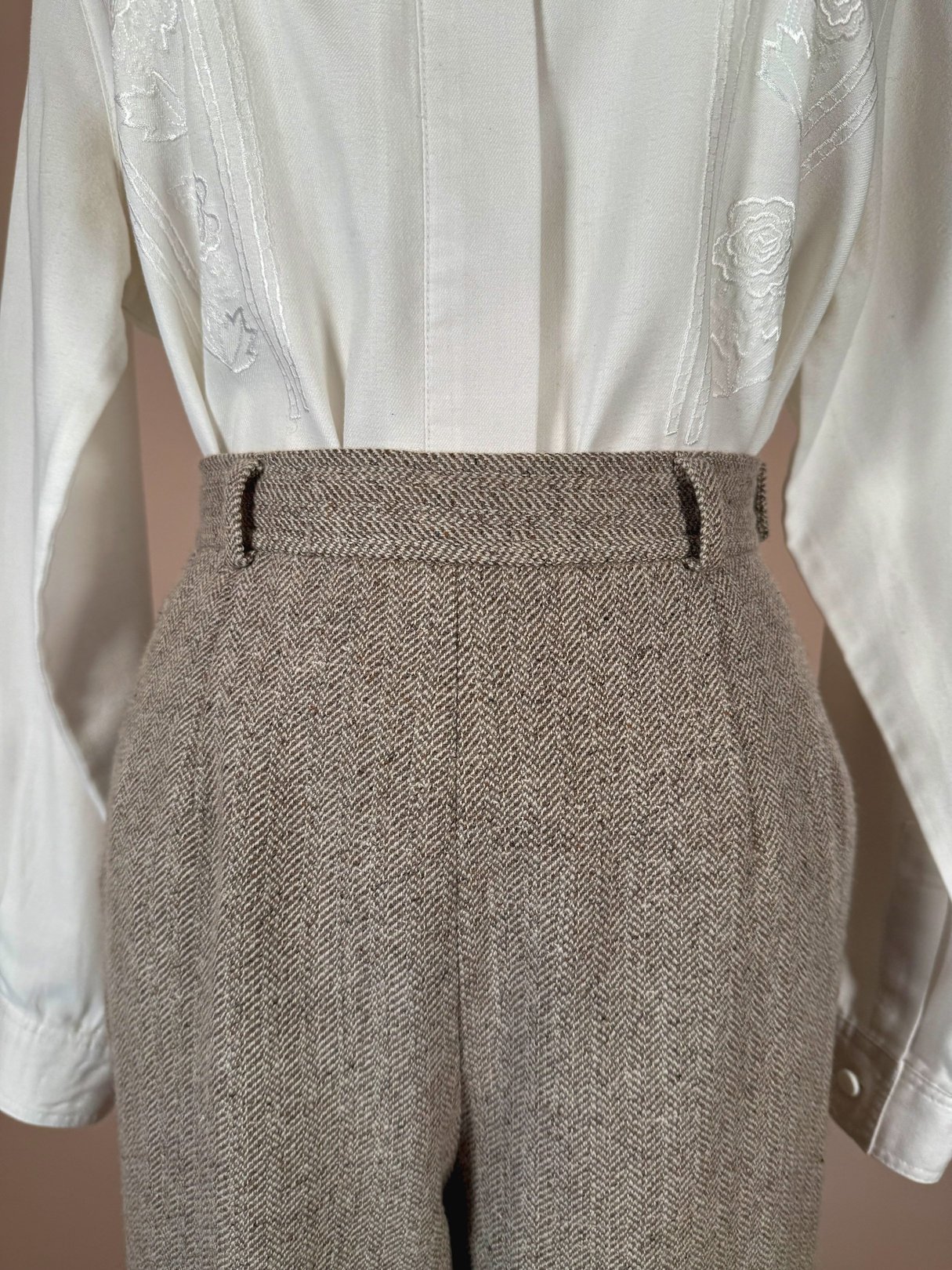 Tan birch tweed pants for women from the 1990s with a high waist and herringbone pattern, styled with a white embroidered blouse.
