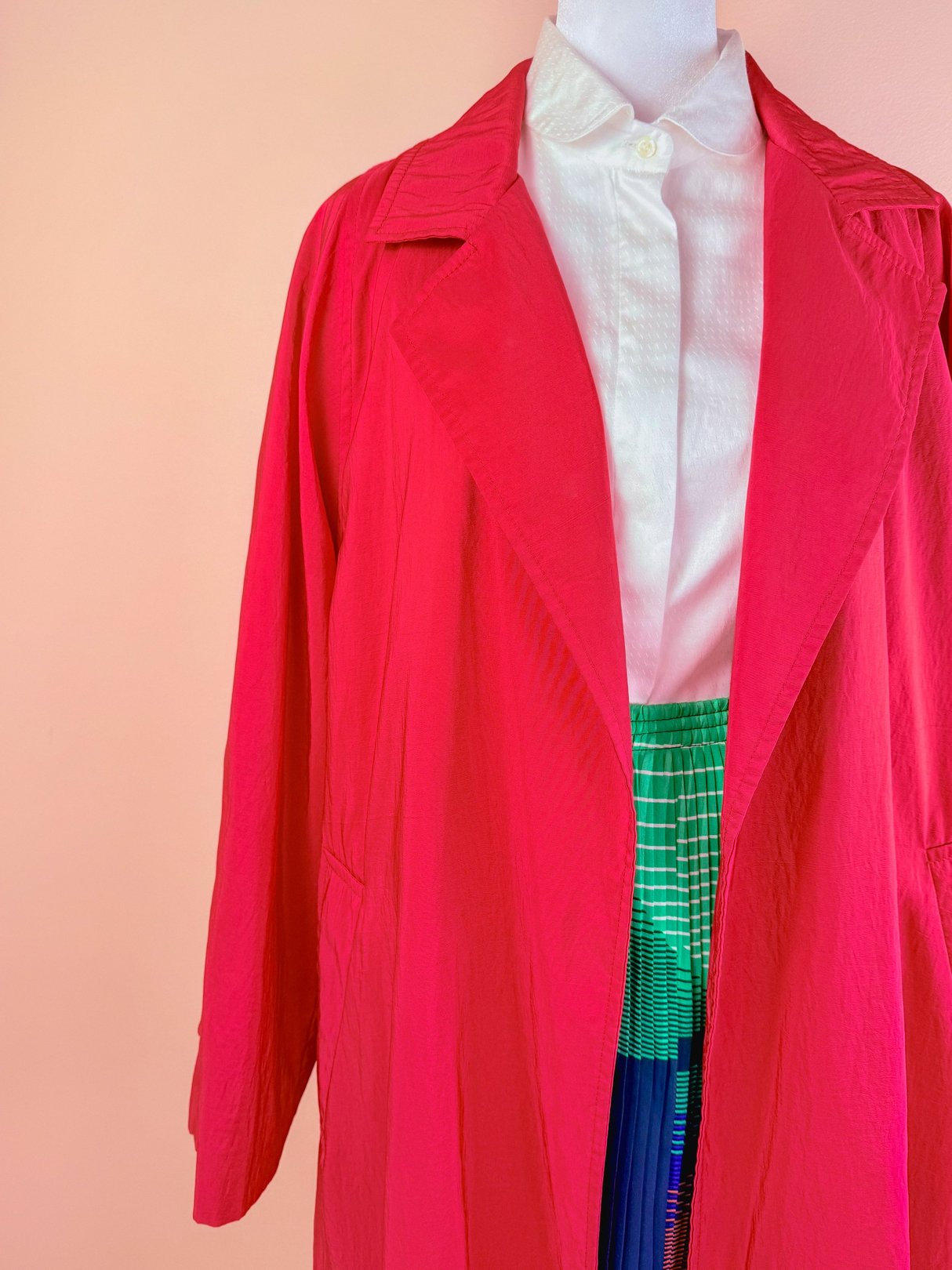 A women's red 1980s Poppy Forecast rain jacket displayed on a mannequin, featuring a collared design and loose fit.