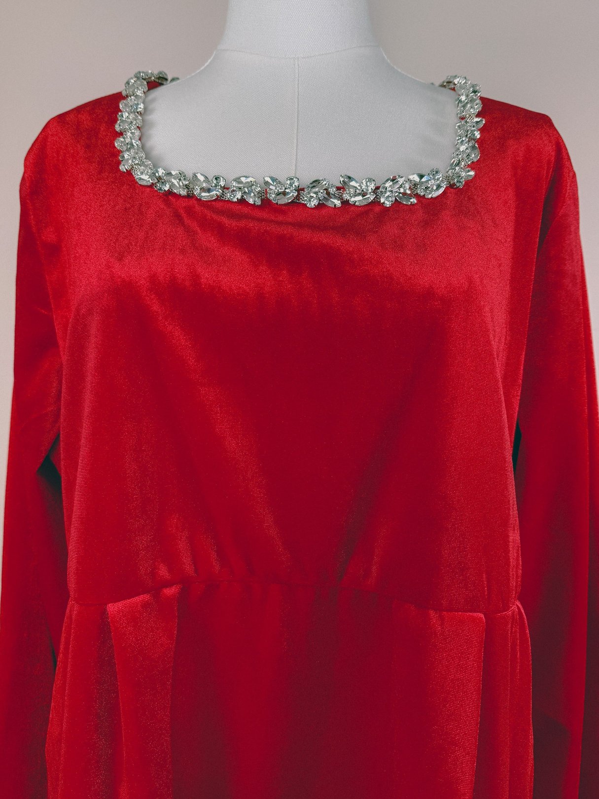 Red velvet dress with a square neckline adorned with a sparkling rhinestone trim, reflecting a 1970s style for women.