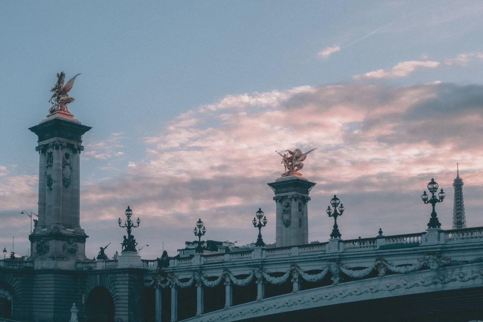 A decorative bridge with ornate lamp posts under a cloudy sky.