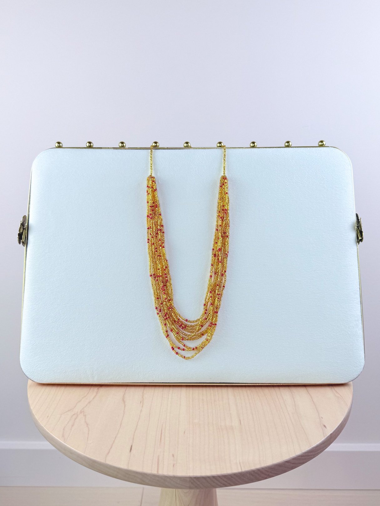 A shimmering gold Marigold Necklace with multiple strands displayed against a white background.