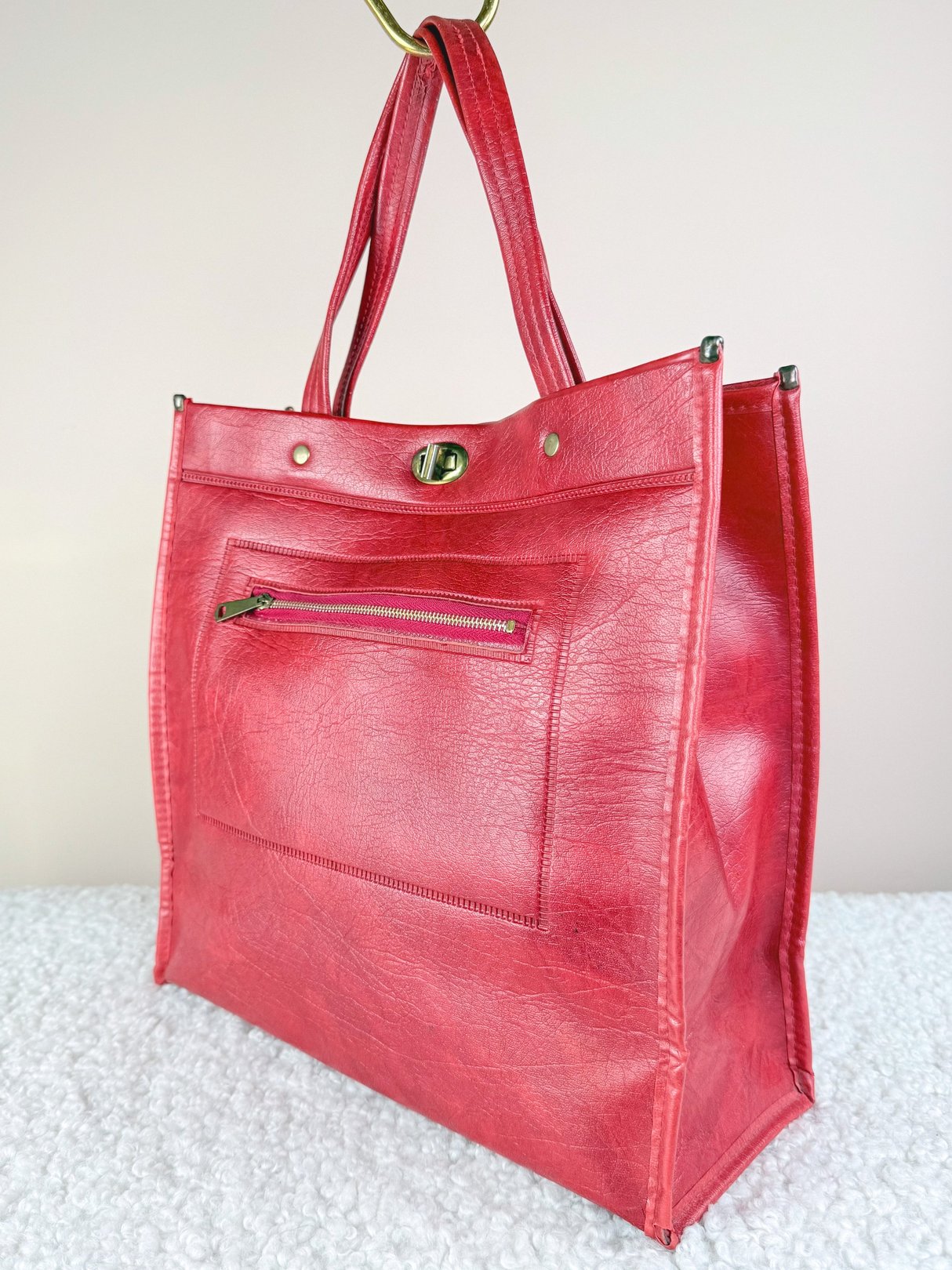 A red 1970s-inspired retro satchel tote bag for women featuring a front zipper pocket and two handles.