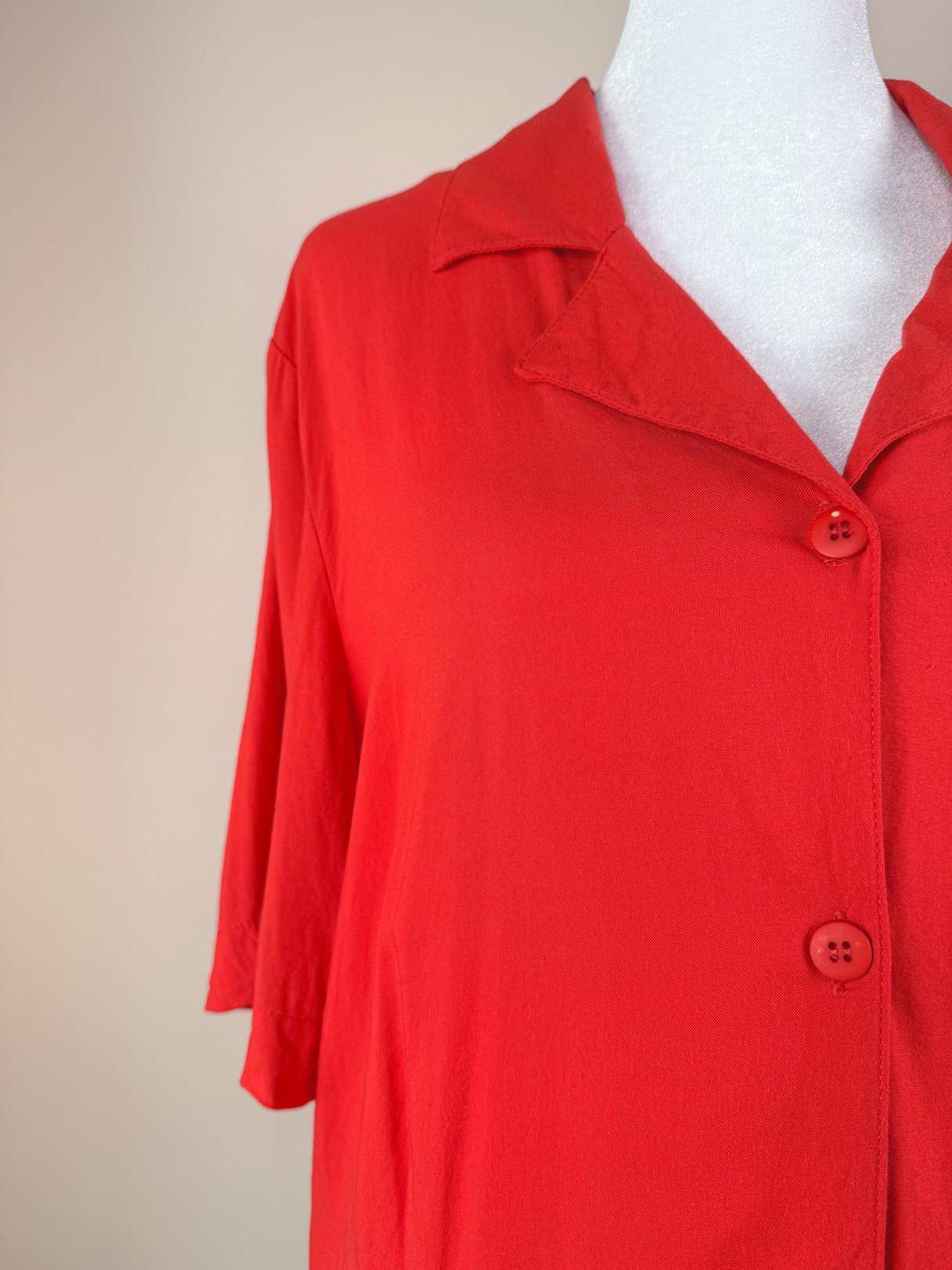 Red 1980s women's top featuring a collar and button closure.